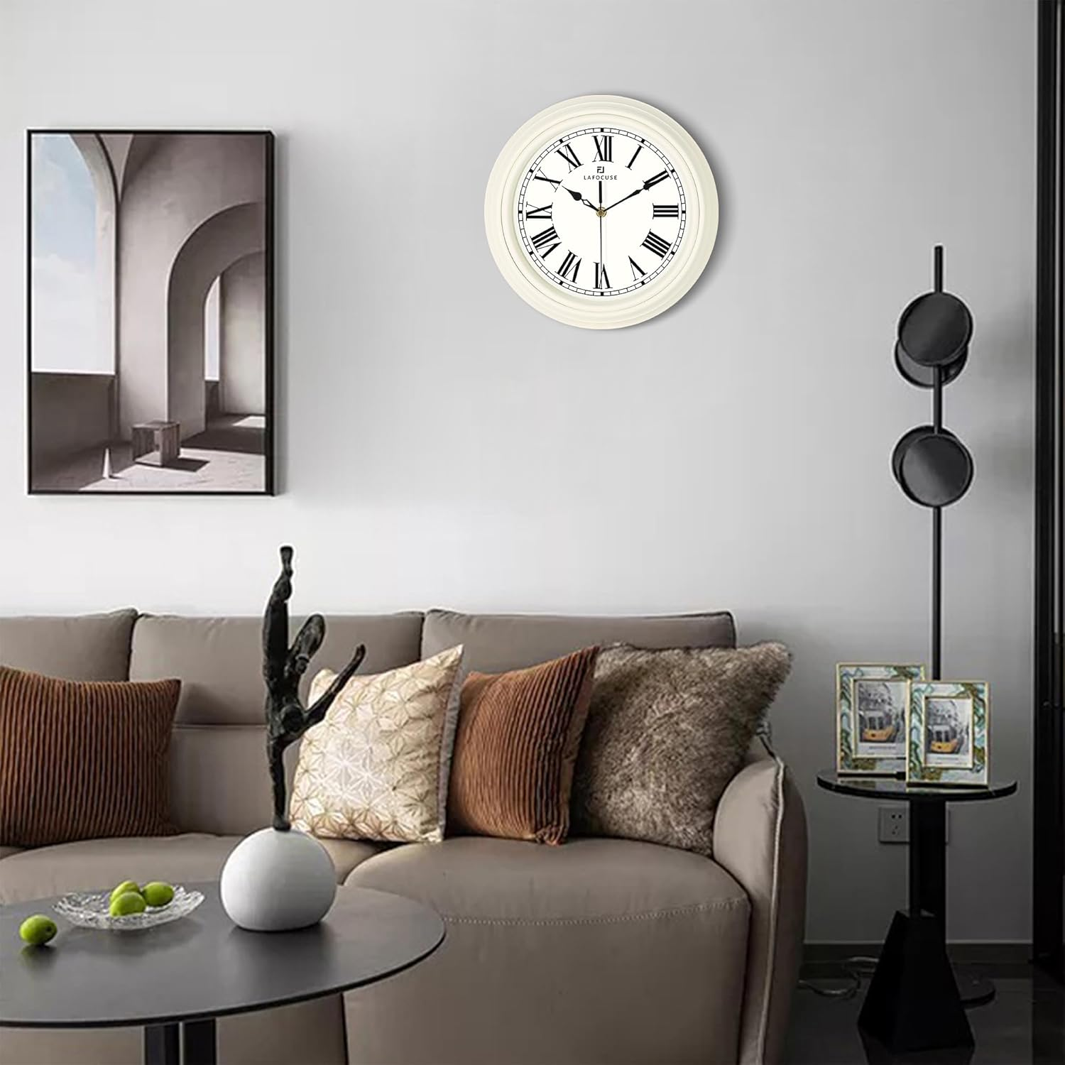 Wohnzimmer mit grauem Sofa, dekorativen Kissen, runder Wanduhr, Kunstwerk und Kaffeetisch.