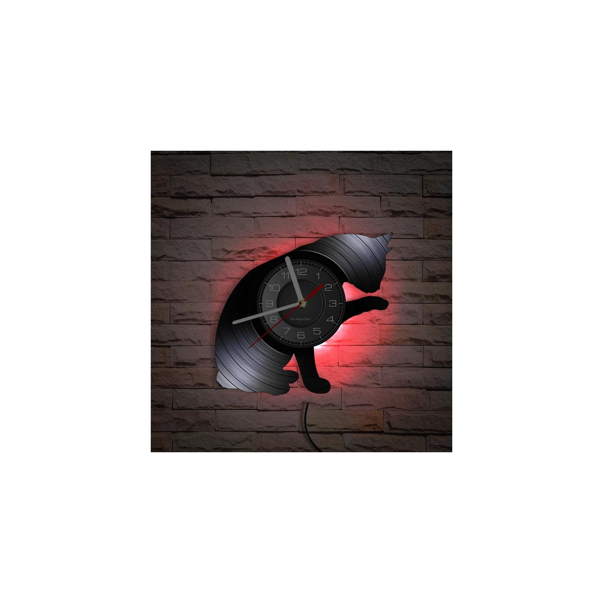 Eine schwarze Vinyl-Wanduhr in Katzenform hängt an einer dunklen Ziegelwand, beleuchtet von rotem LED-Licht.