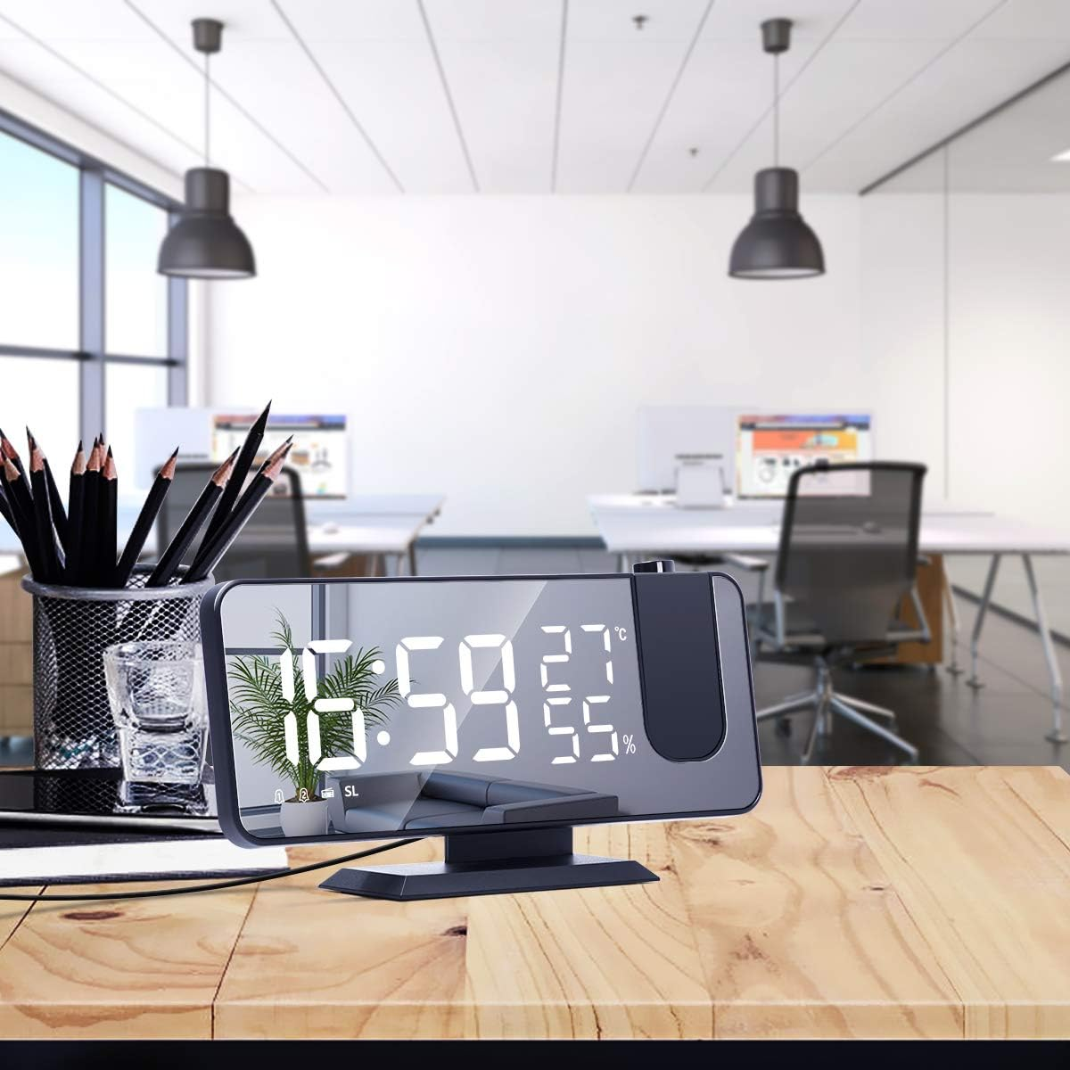 Digitale Projektionsuhr auf einem Holztisch mit Stiften und Büro im Hintergrund.