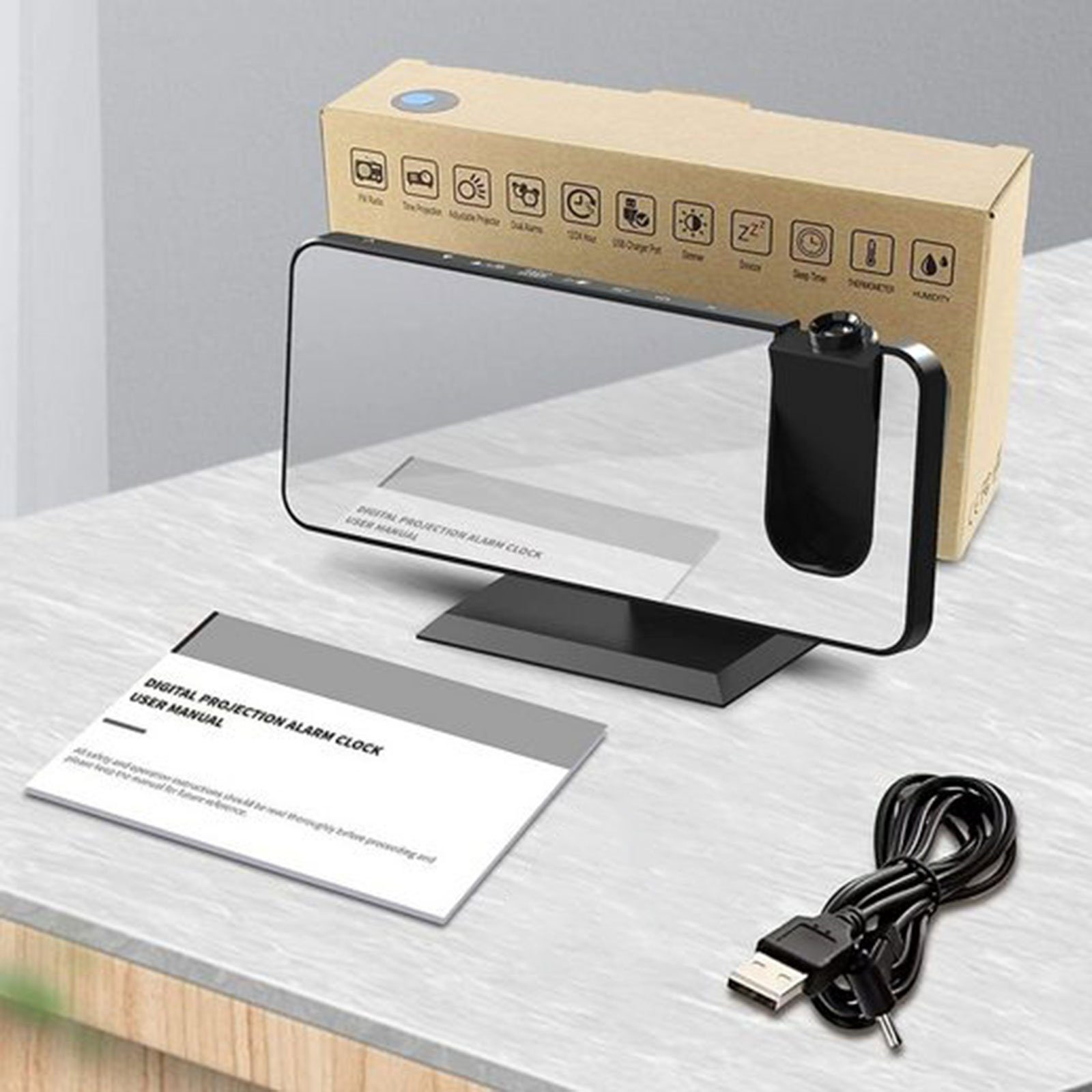 Digitale Projektionsuhr mit Verpackungskarton, Handbuch und USB-Kabel auf einem Tisch.