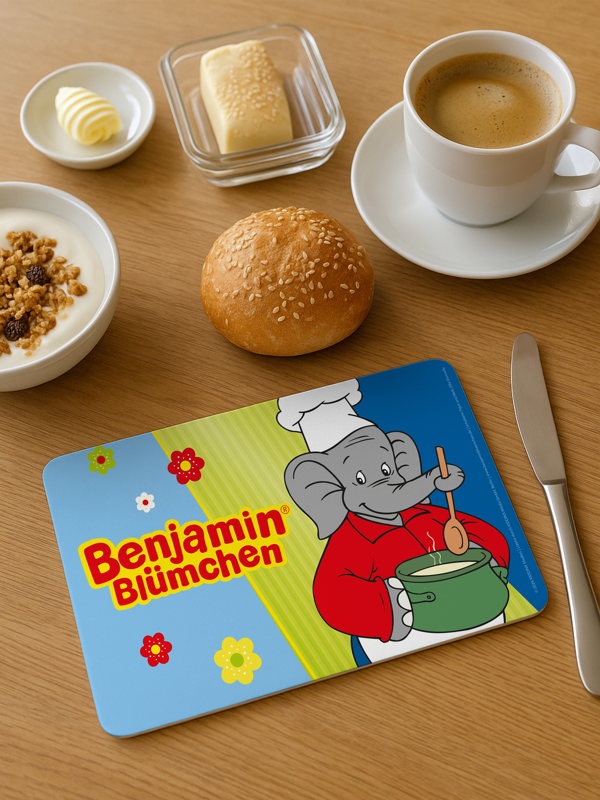 Frühstückstisch mit Brötchen, Joghurt, Butter, Kaffee und einer Benjamin Blümchen Tischset.