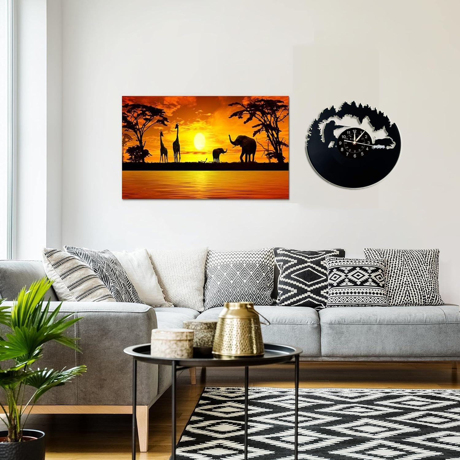 Ein Wohnzimmer mit grauem Sofa, gemusterten Kissen, schwarzem Couchtisch und Tierdekor an der Wand.