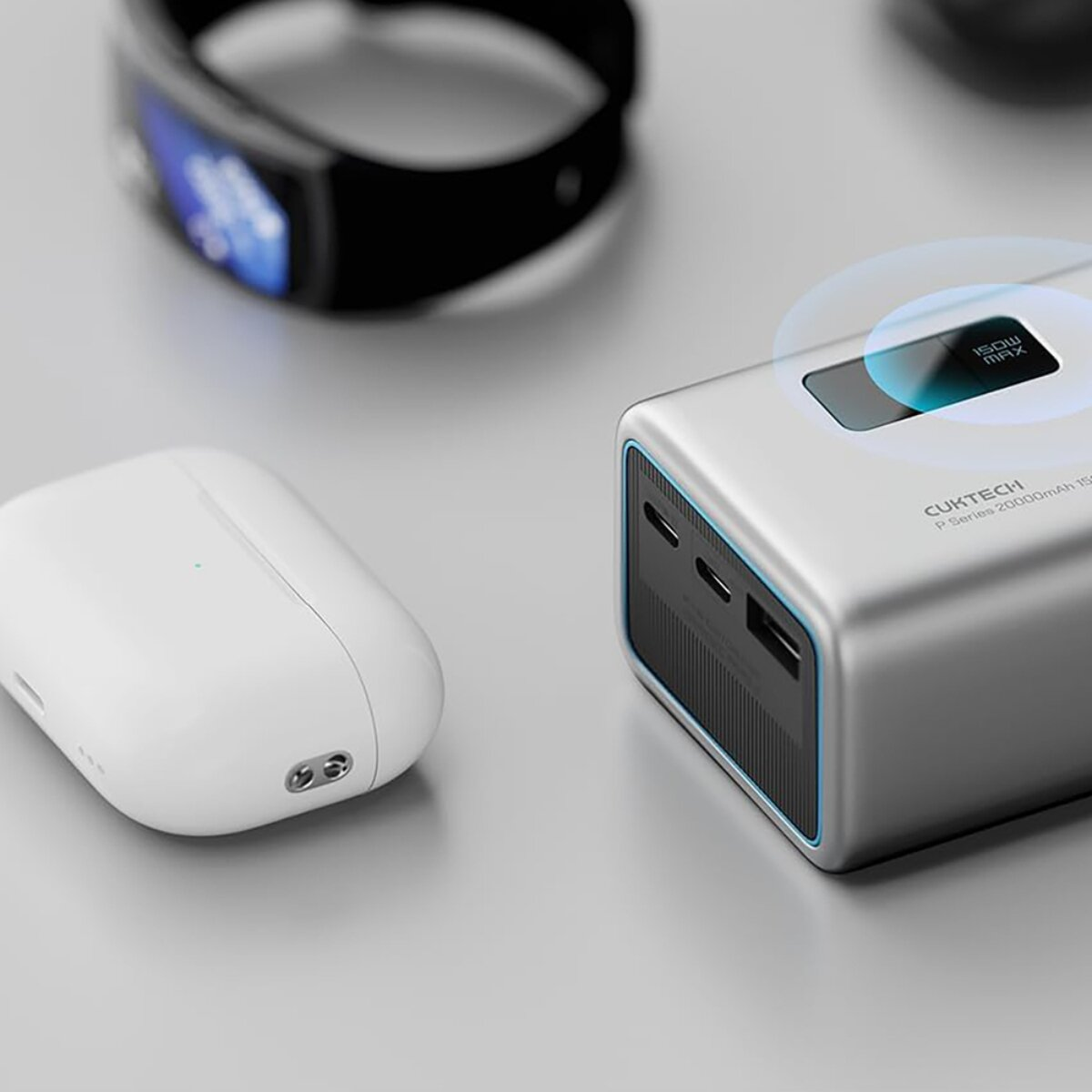 Una power bank argentata Cuktech, auricolari bianchi in una custodia e una smart band nera.