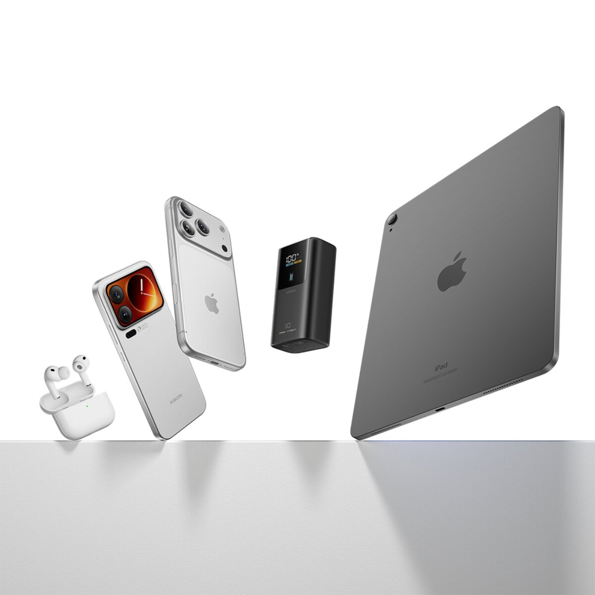 Verschiedene Elektronikgeräte wie Kopfhörer, Smartphones, eine Powerbank und ein Tablet stehen auf einer weißen Fläche.