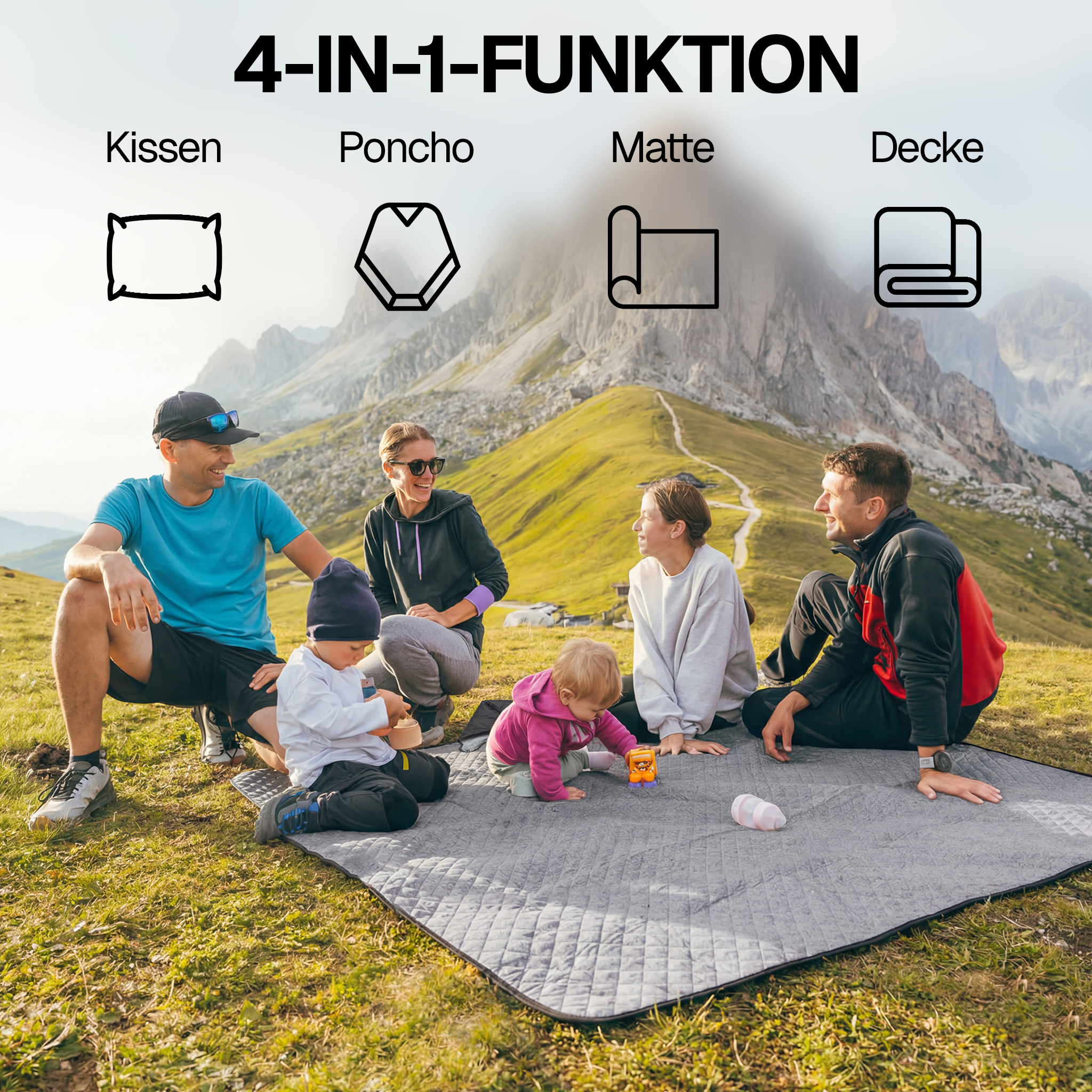 Eine Familie mit zwei Kindern sitzt auf einer grauen Matte in den Bergen.