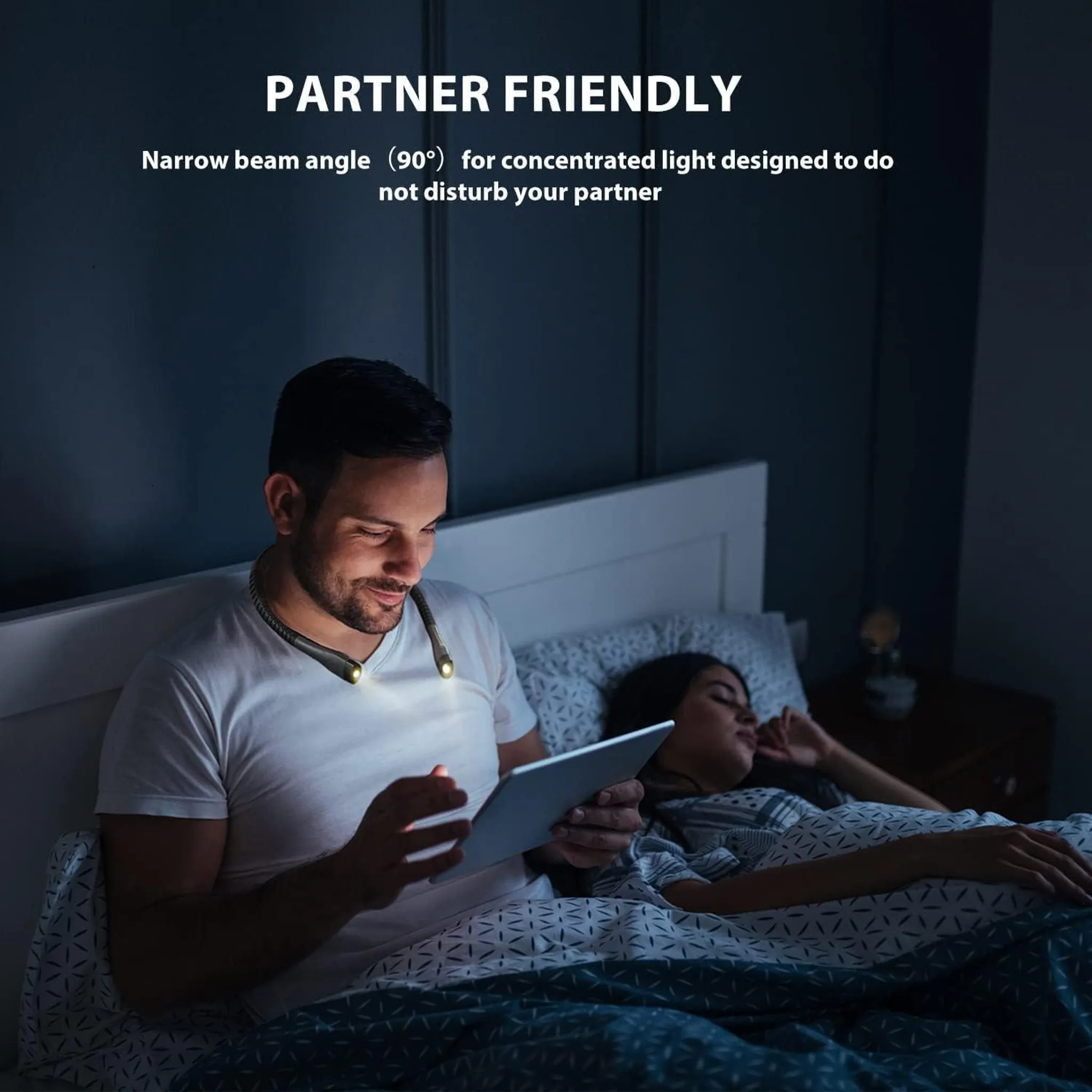 Ein Mann im Bett liest mit einer Nackenlampe ein Tablet, während daneben eine Frau schläft.