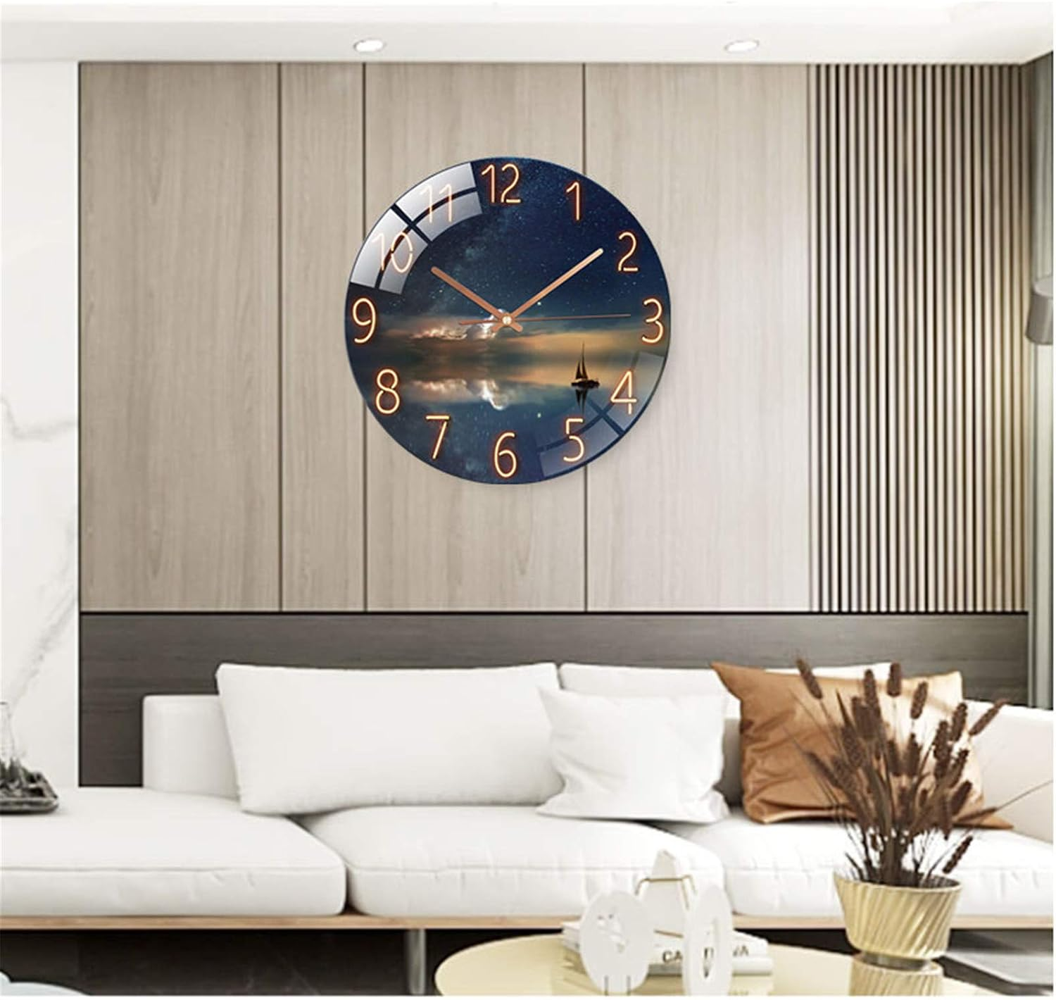 Eine runde Wanduhr mit Sternenhimmel-Landschaft hängt über einem weißen Sofa in einem Wohnzimmer.