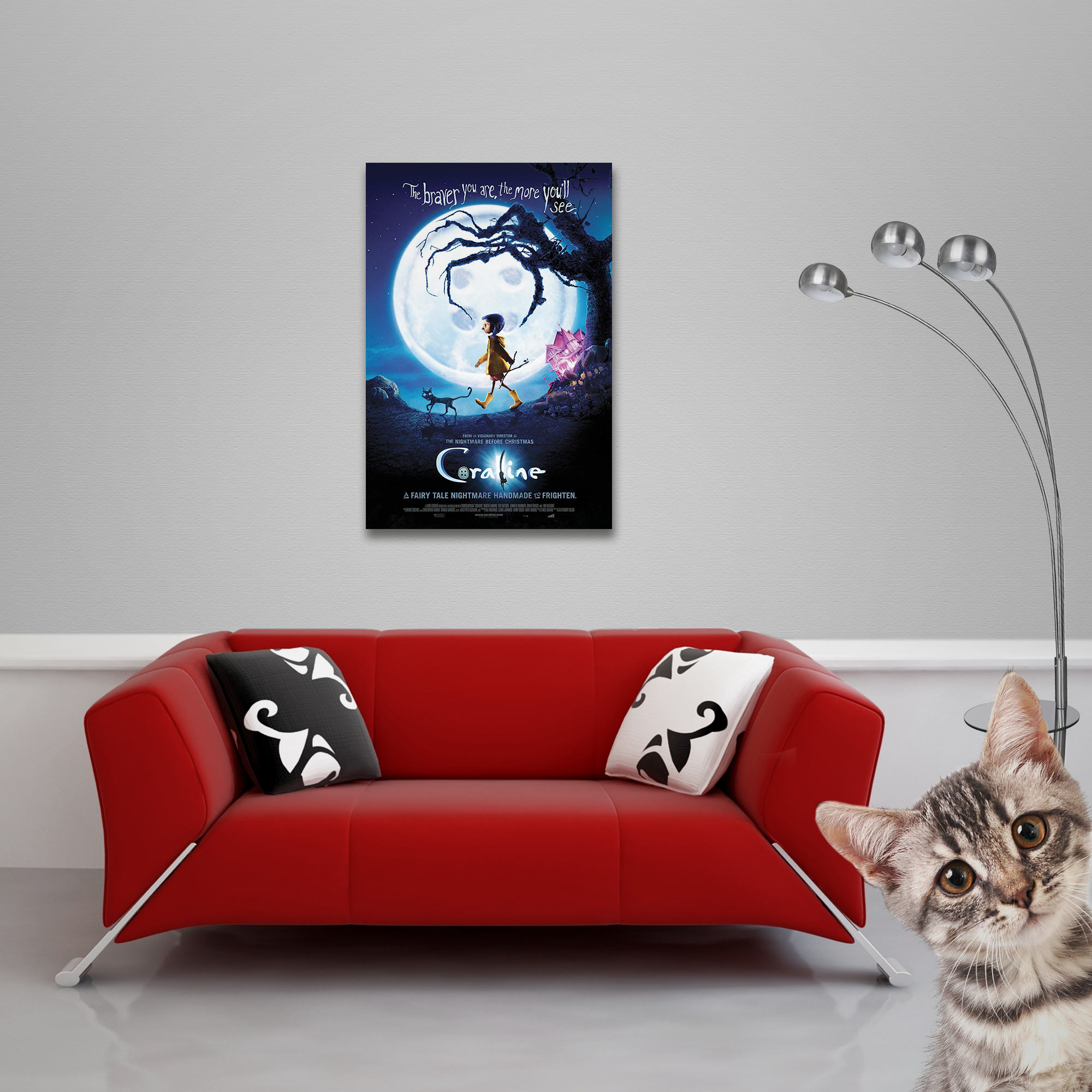 Ein rotes Sofa steht unter einem Coraline-Poster an einer grauen Wand, neben Lampe und Katze.