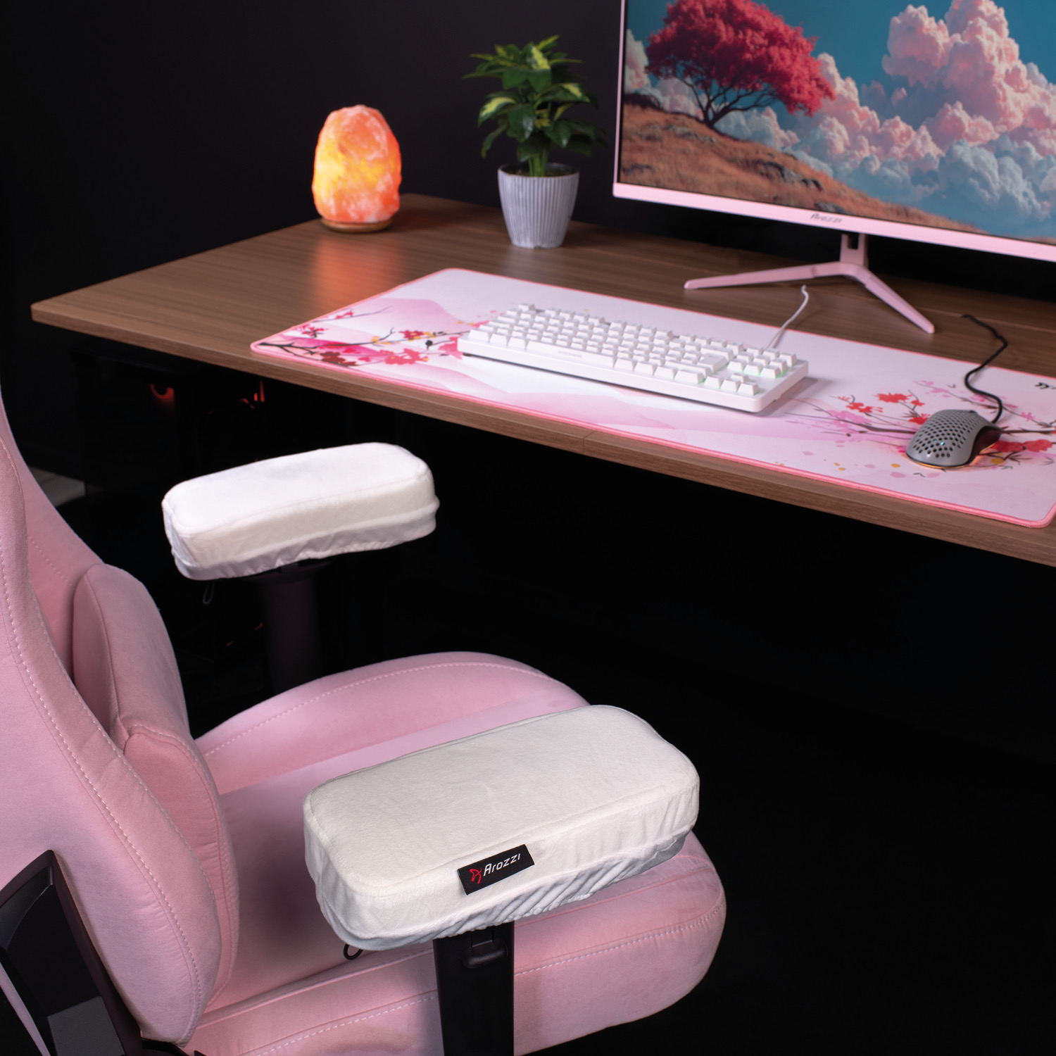 Sedia da gioco rosa con cuscini per braccioli bianchi di fronte a una scrivania.
