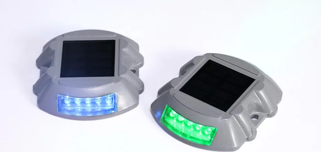 Zwei graue Solar-Wegebegrenzungen mit eingebauten Solarpaneelen, eine mit blauen LEDs, die andere mit grünen LEDs.
