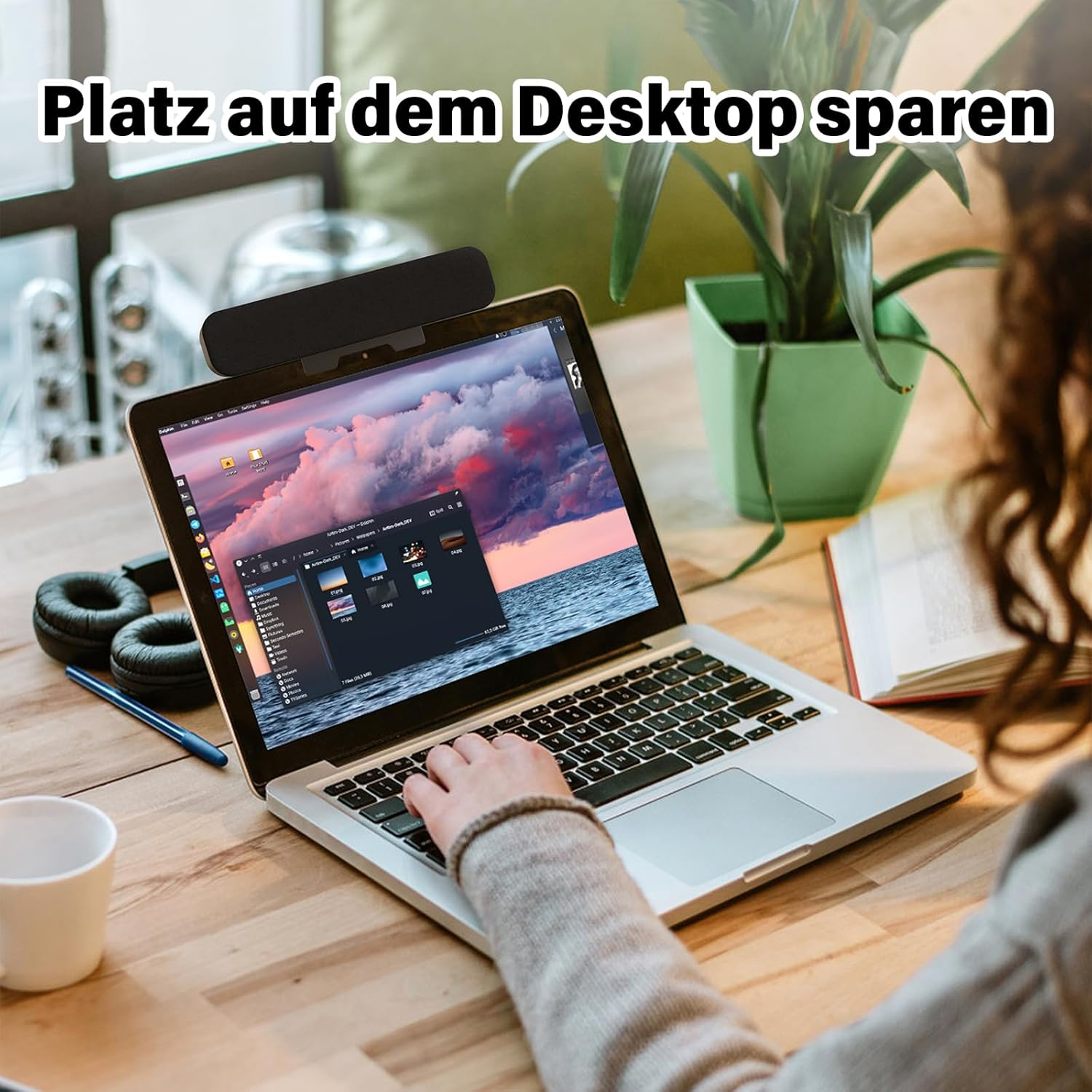 Eine Frau arbeitet an einem Laptop am Holztisch mit Lampe, Pflanzen und Kopfhörern.
