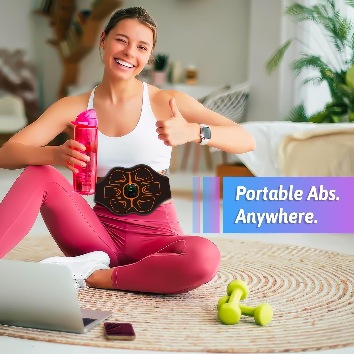 Frau lächelt, sitzt auf Matte, trägt EMS-Bauchgurt, hält pinke Flasche, zeigt Daumen hoch vor Laptop und Hanteln.