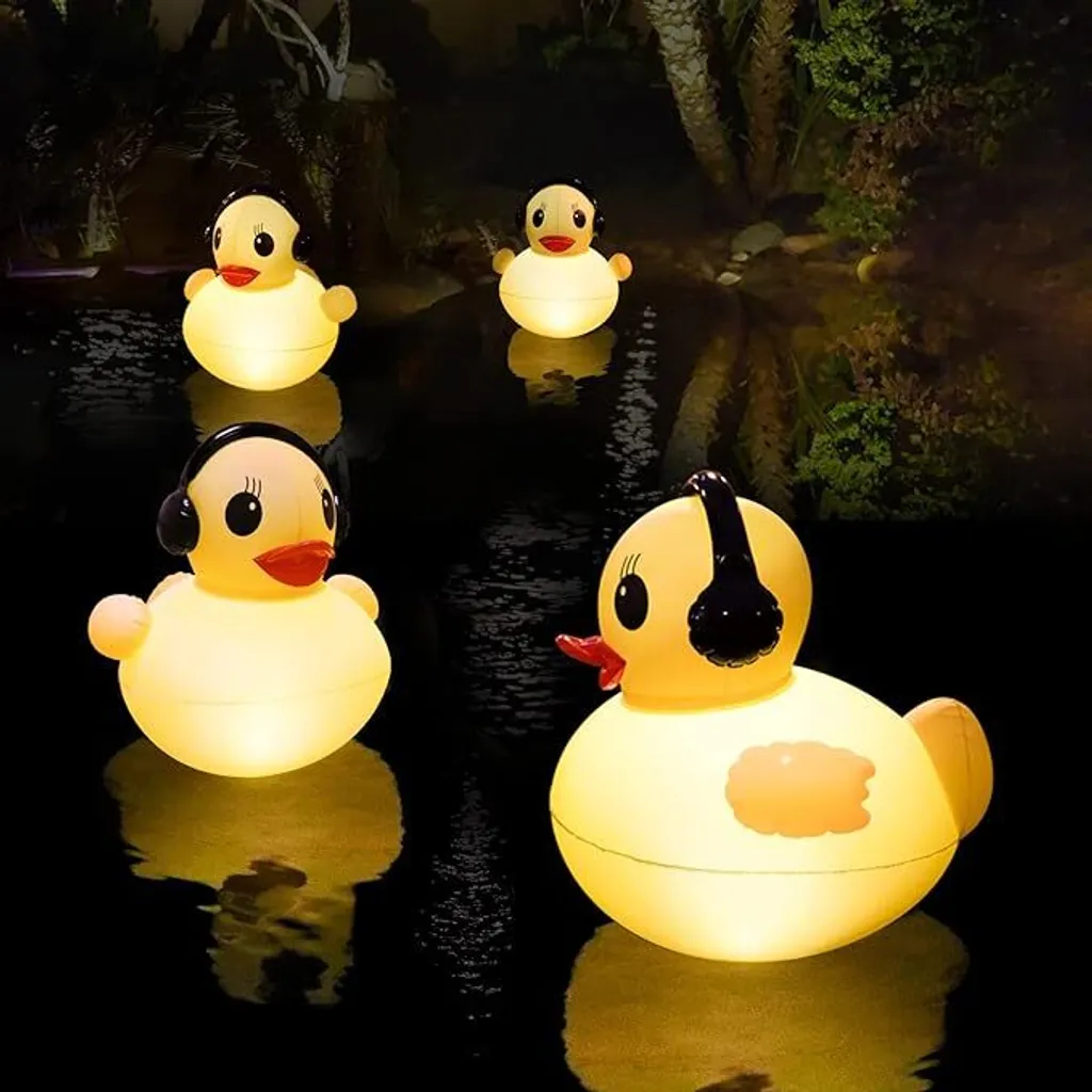 Vier leuchtende gelbe Enten mit schwarzen Kopfhörern schwimmen nachts in einem dunklen Teich vor Bäumen.