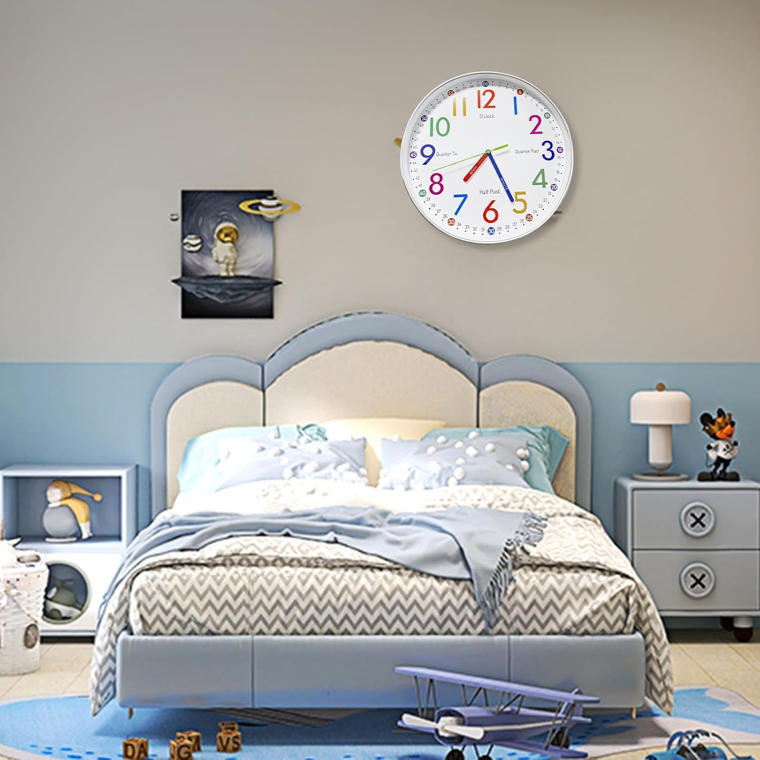 Buntes Kinderzimmer mit Bett, Lernwanduhr, Raumschiffbild und Spielzeug.