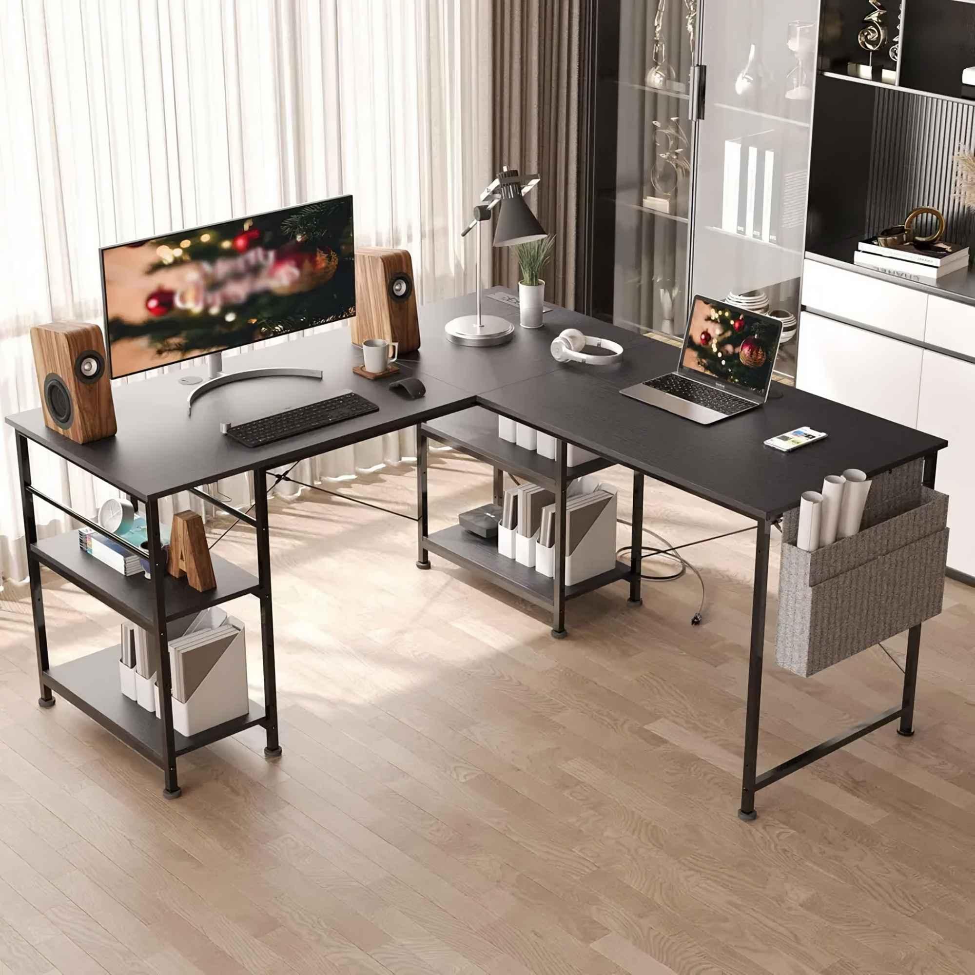 Ein schwarzer L-förmiger Schreibtisch mit Monitor, Laptop, Holzboxen und Regalen im Hintergrund.