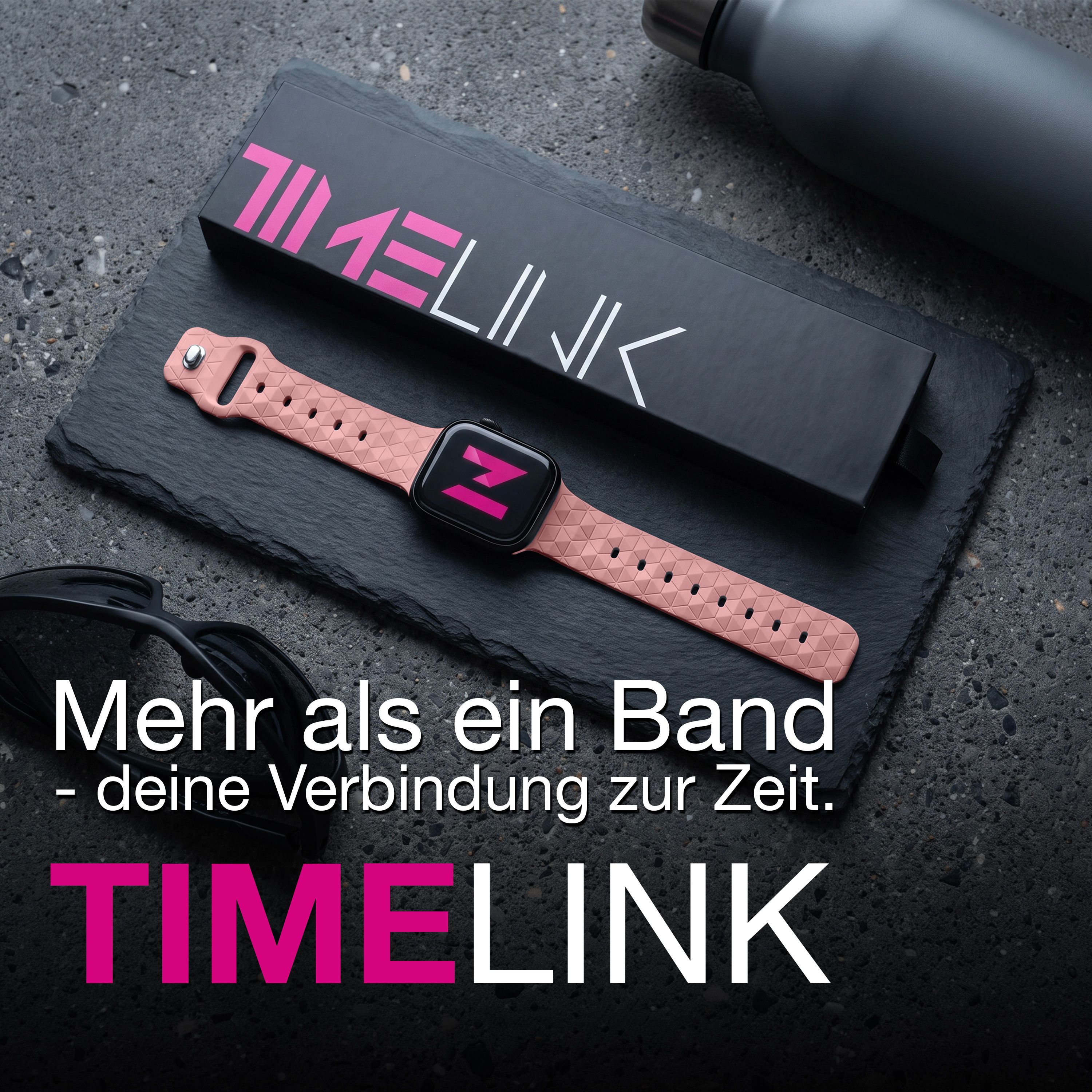 Rosa Smartwatch auf schwarzem Schiefer neben Verpackung und Sonnenbrille.