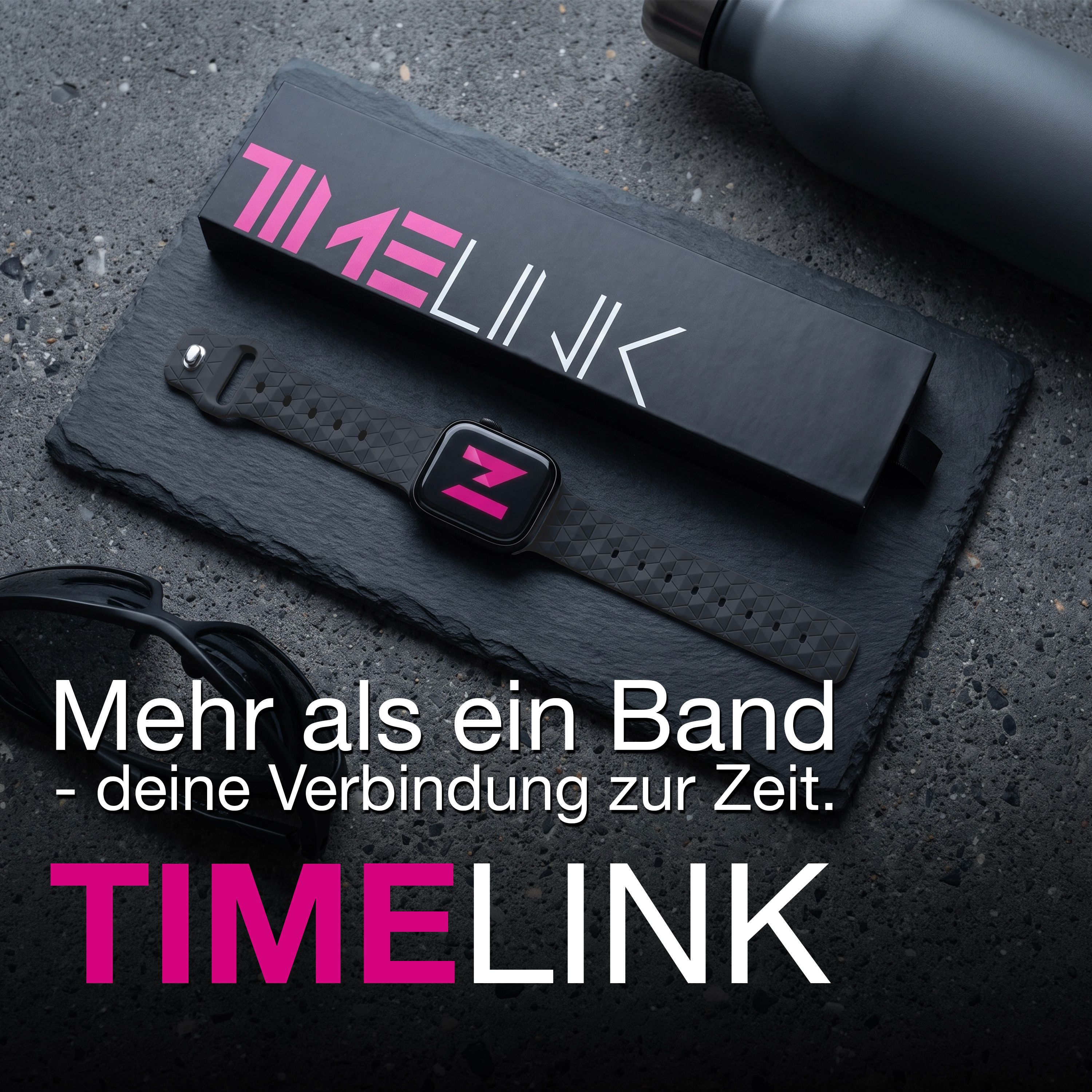 Eine Smartwatch mit gemustertem Armband und Box auf dunklem Schiefer mit Sonnenbrille, Flasche und Text.
