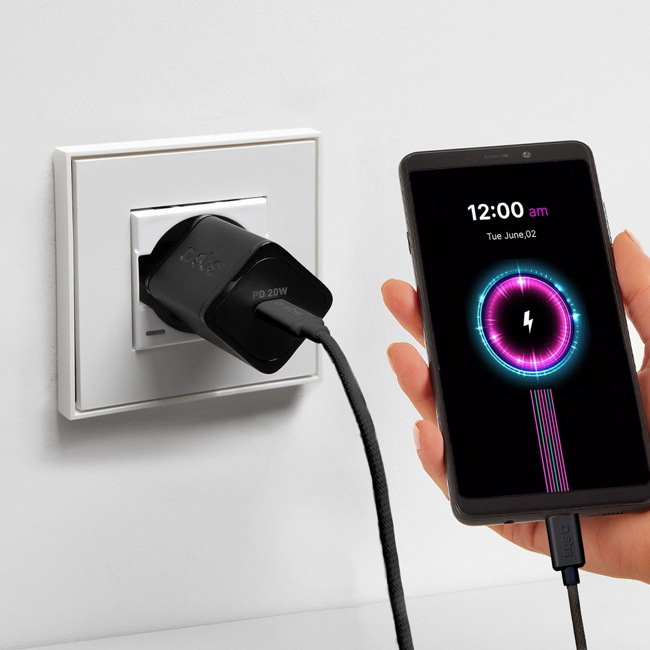 Un cargador negro enchufado a la pared carga un teléfono inteligente con pantalla brillante.