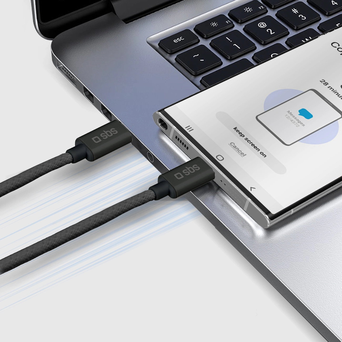Dos cables negros están conectados a una computadora portátil y un teléfono inteligente que descansa sobre el teclado.