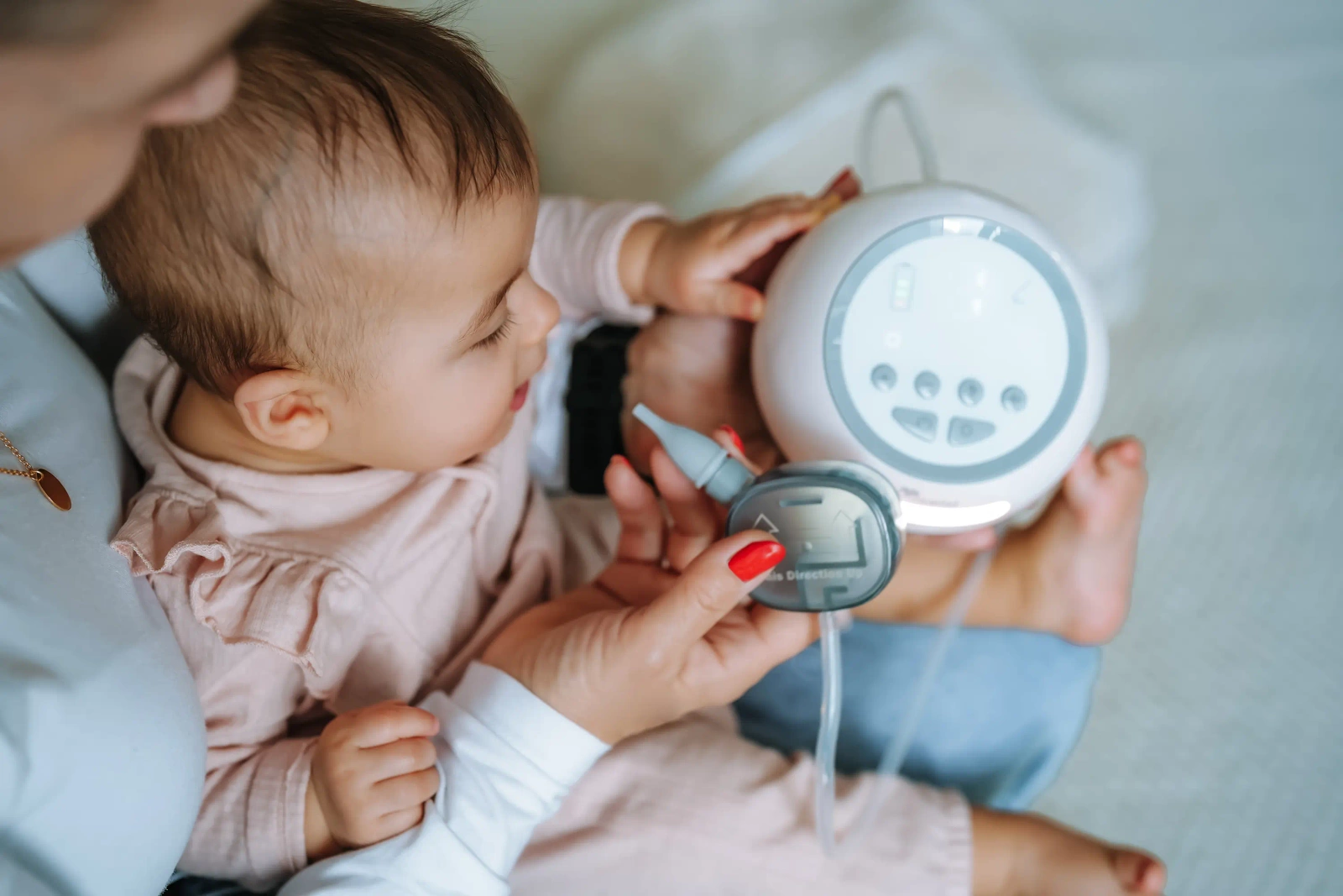 Una donna tiene un tiralatte vicino a un neonato con una tutina rosa.