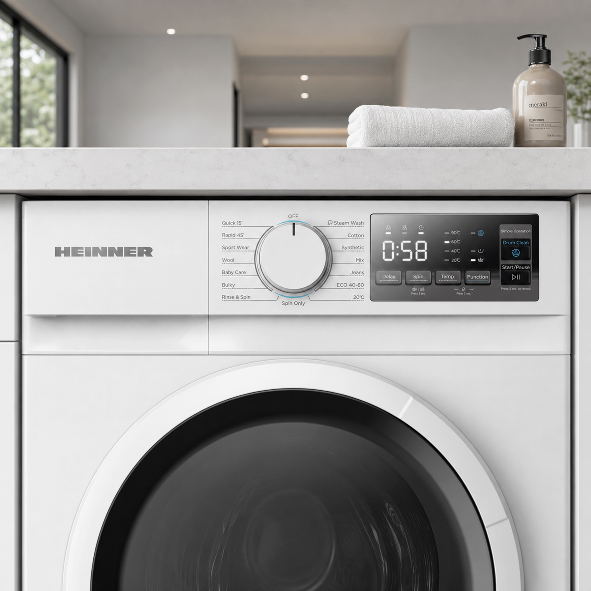 Gros plan d'un lave-linge blanc Heinner avec panneau de commande, sélecteur, écran numérique et une serviette.