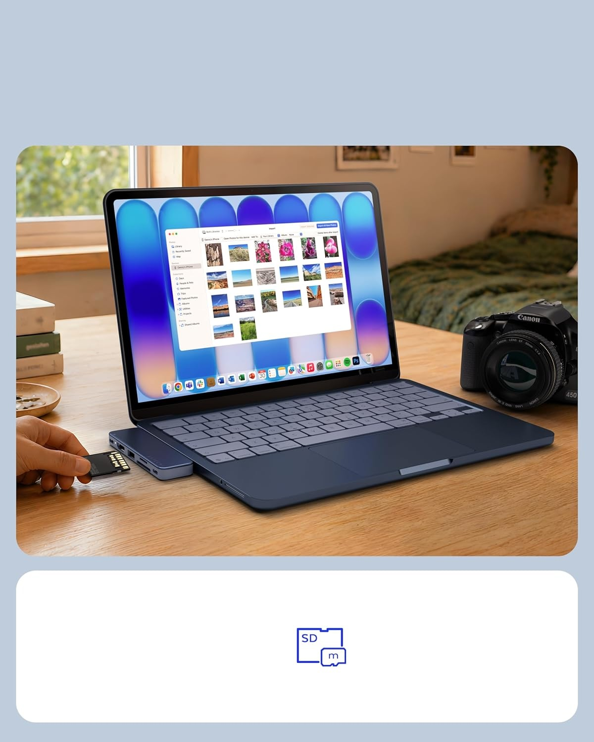 Niebieski laptop na drewnianym biurku, ktoś wsuwa kartę SD, obok aparat.