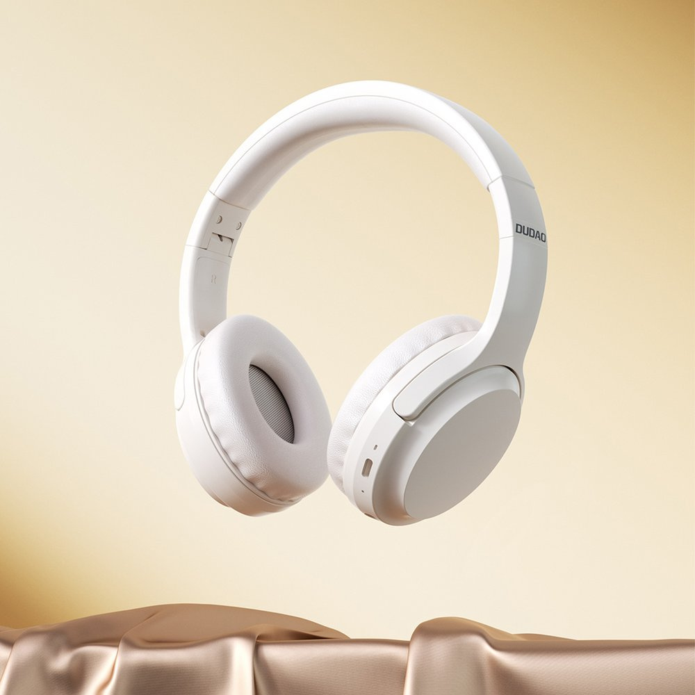 Cuffie over-ear bianche fluttuano davanti a uno sfondo dorato e serico.