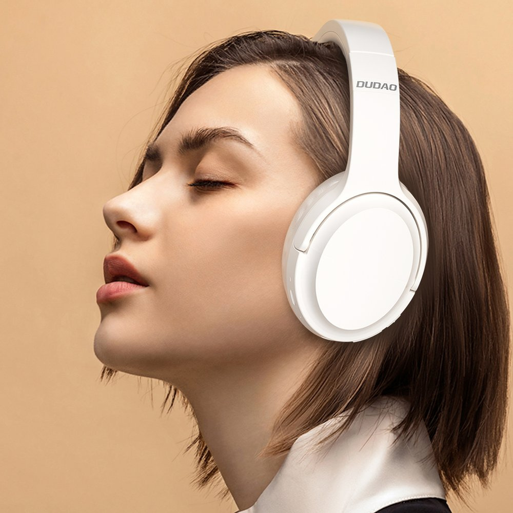 Una donna con gli occhi chiusi indossa cuffie bianche Dudao su sfondo beige.
