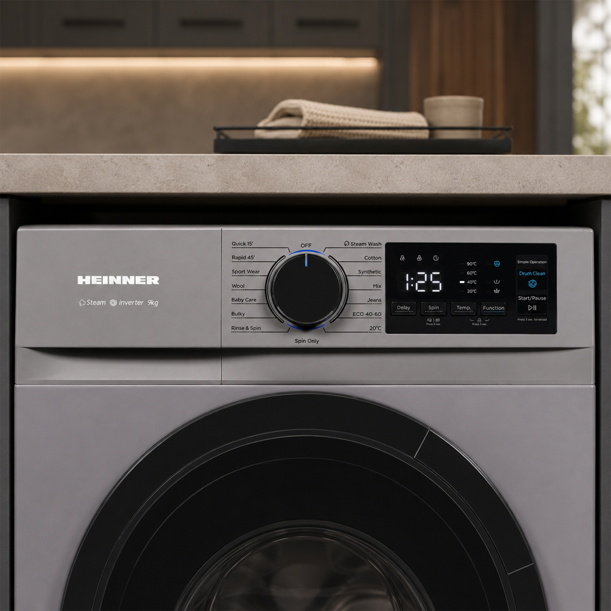 Lave-linge gris Heinner sous un plan de travail avec panneau de contrôle et affichage numérique.