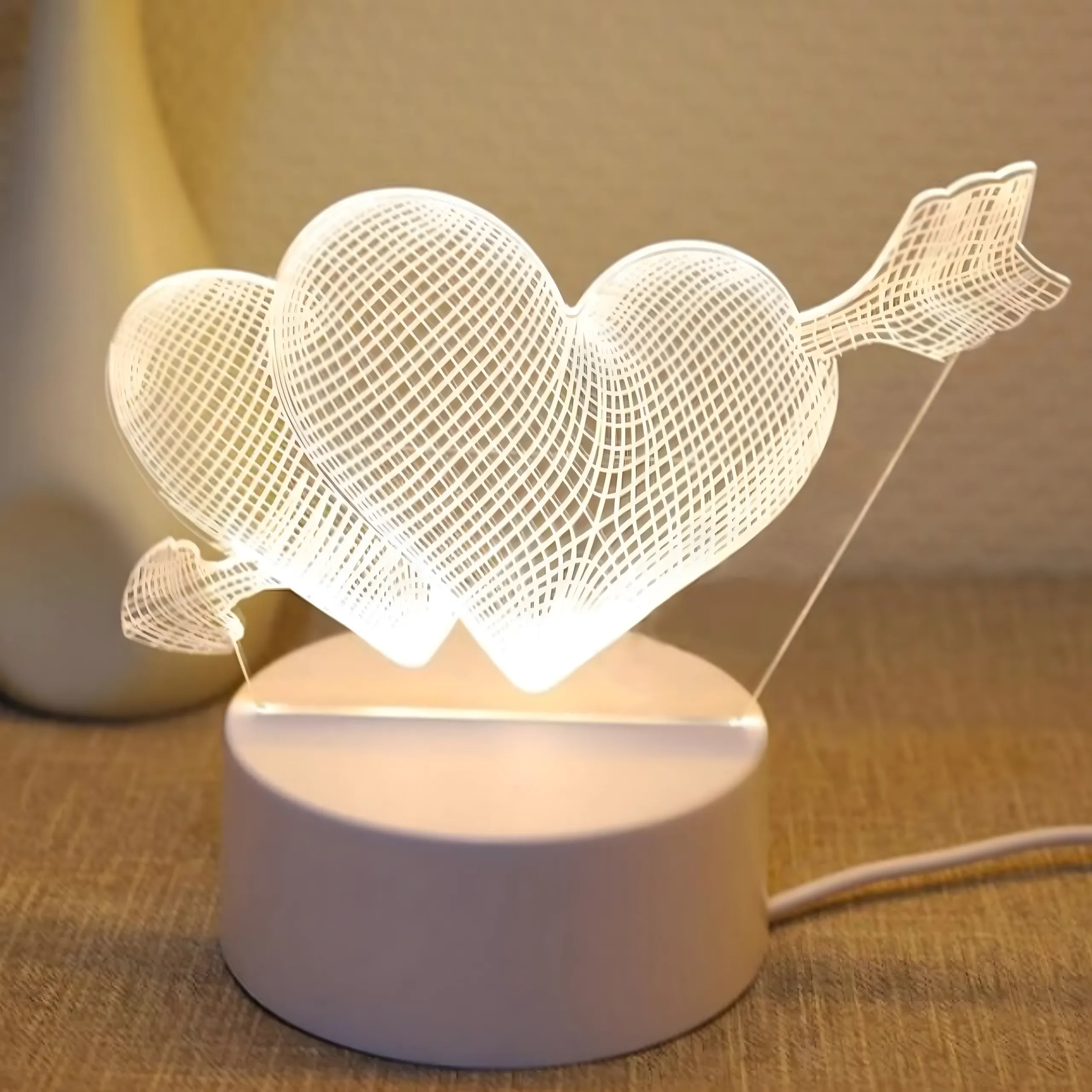 Świetlna lampa akrylowa 3D przedstawia dwa serca przeszyte strzałą na okrągłej podstawie.