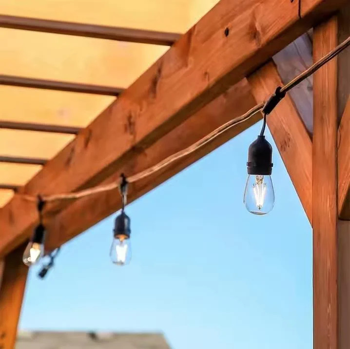 Lampki choinkowe wiszą na drewnianej pergoli pod błękitnym niebem.