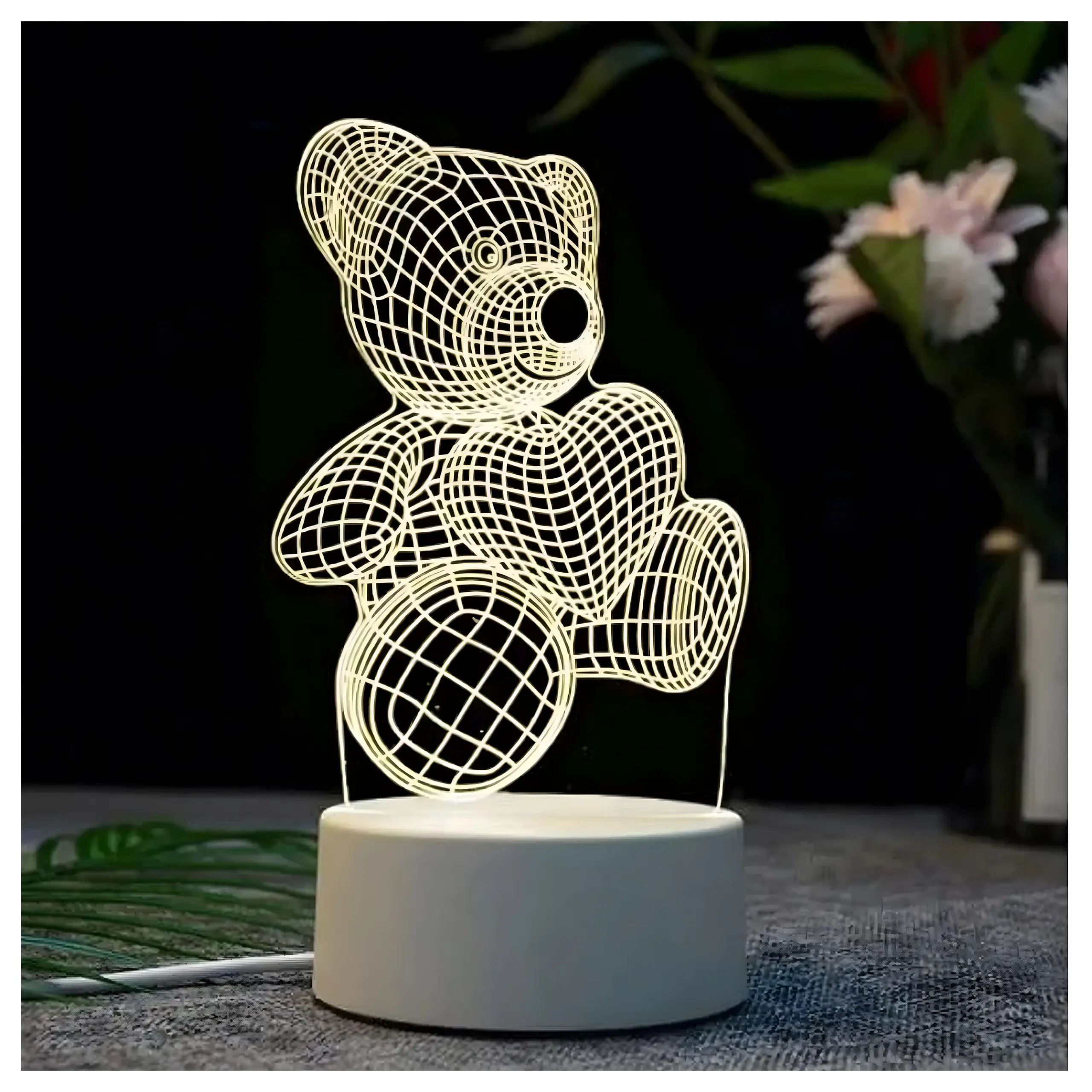 Świetlna lampka 3D przedstawiająca misia z sercem, na białej podstawie, na ciemnym tle.