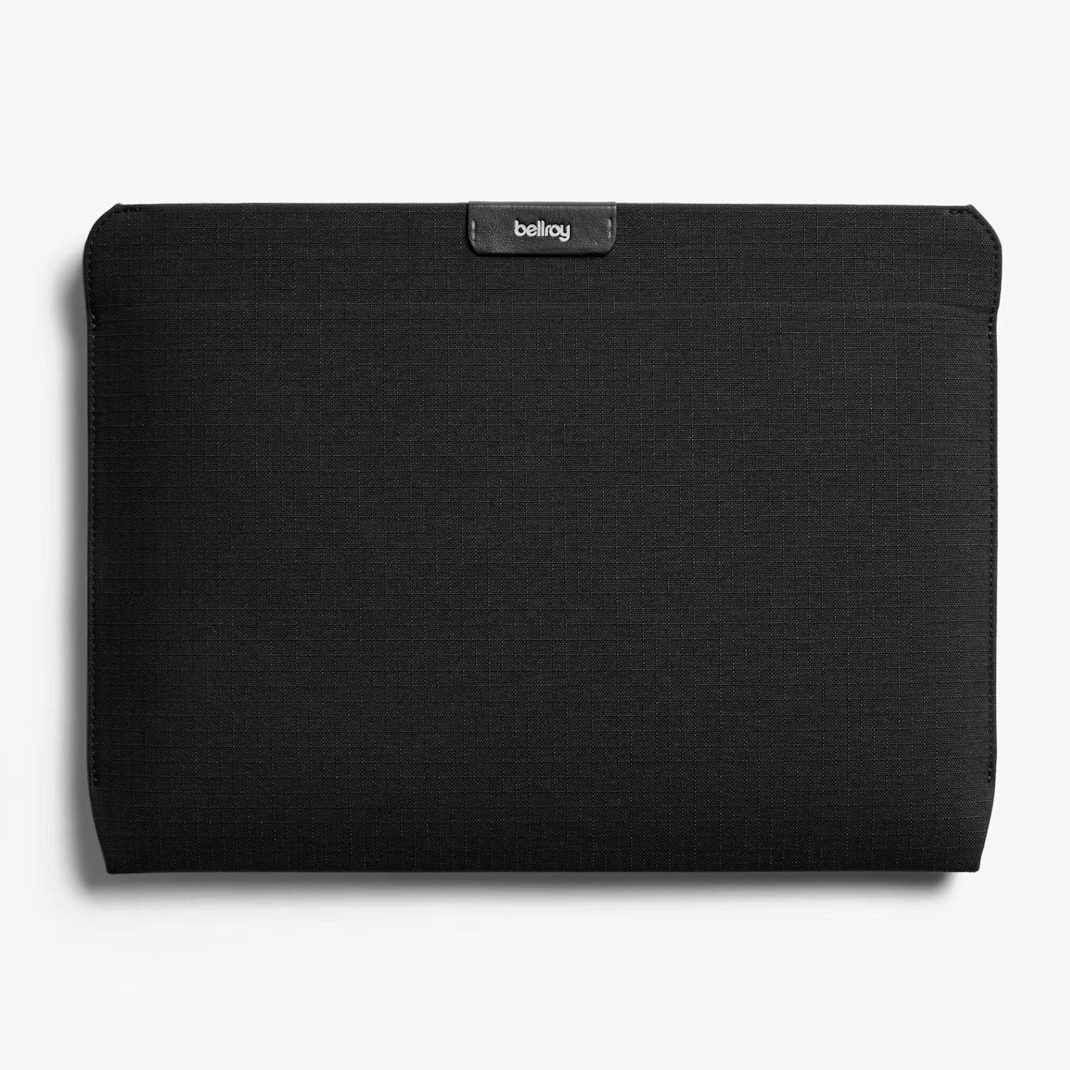 Czarny, fakturowany pokrowiec na laptopa z logo Bellroy na środku u góry, na białym tle.
