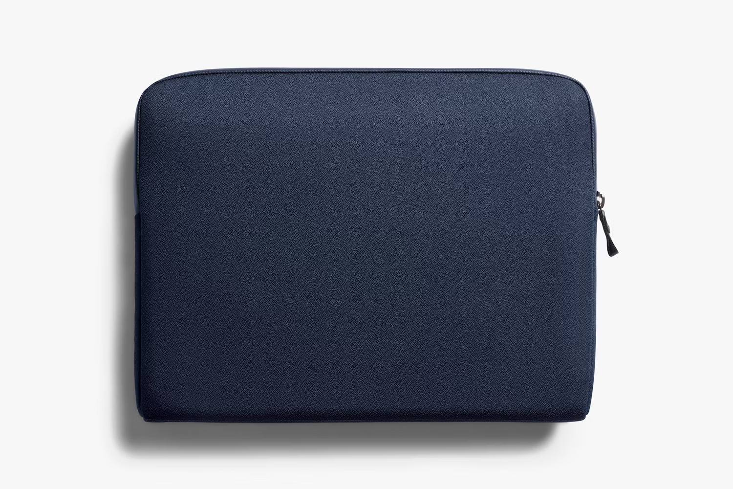 Ciemnoniebieskie etui na laptopa z zamkiem błyskawicznym na jasnym tle.