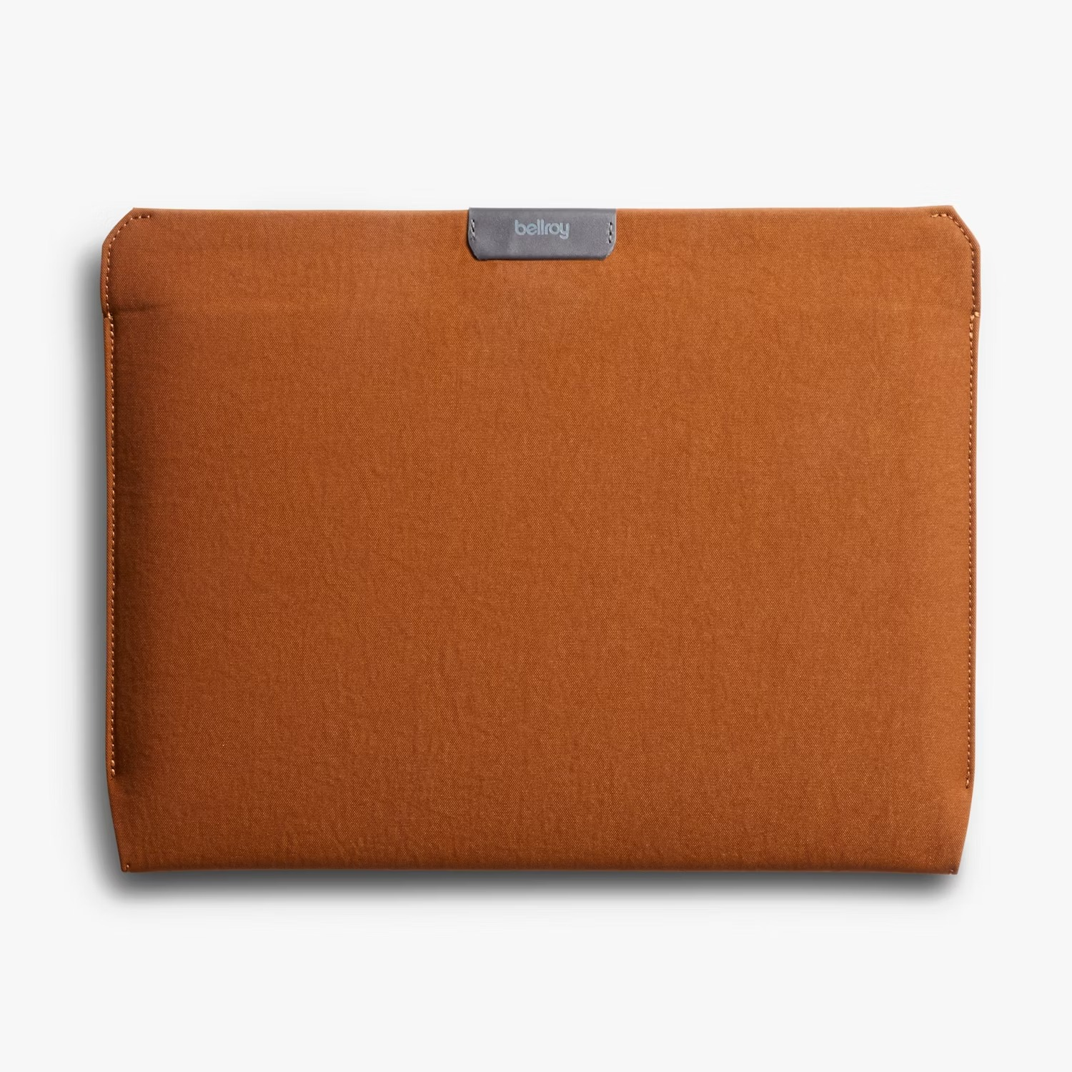 Brązowe materiałowe etui na laptopa z małą szarą skórzaną metką z napisem Bellroy na środku góry, na białym tle.