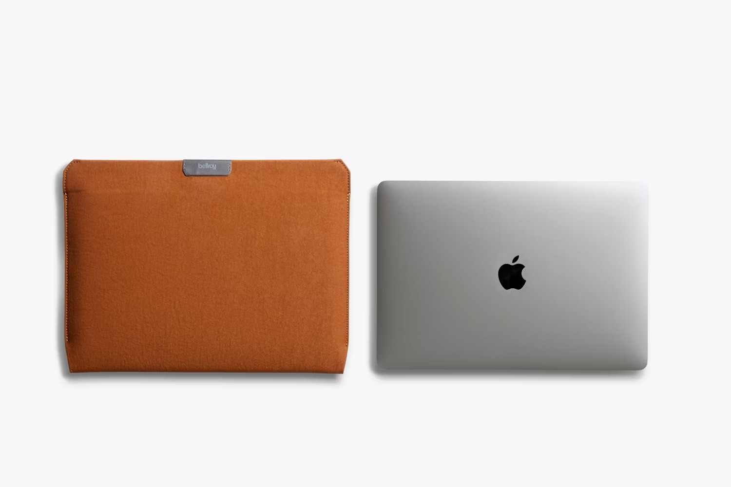 Brązowe filcowe etui na laptopa obok zamkniętego srebrnego laptopa na białym tle.