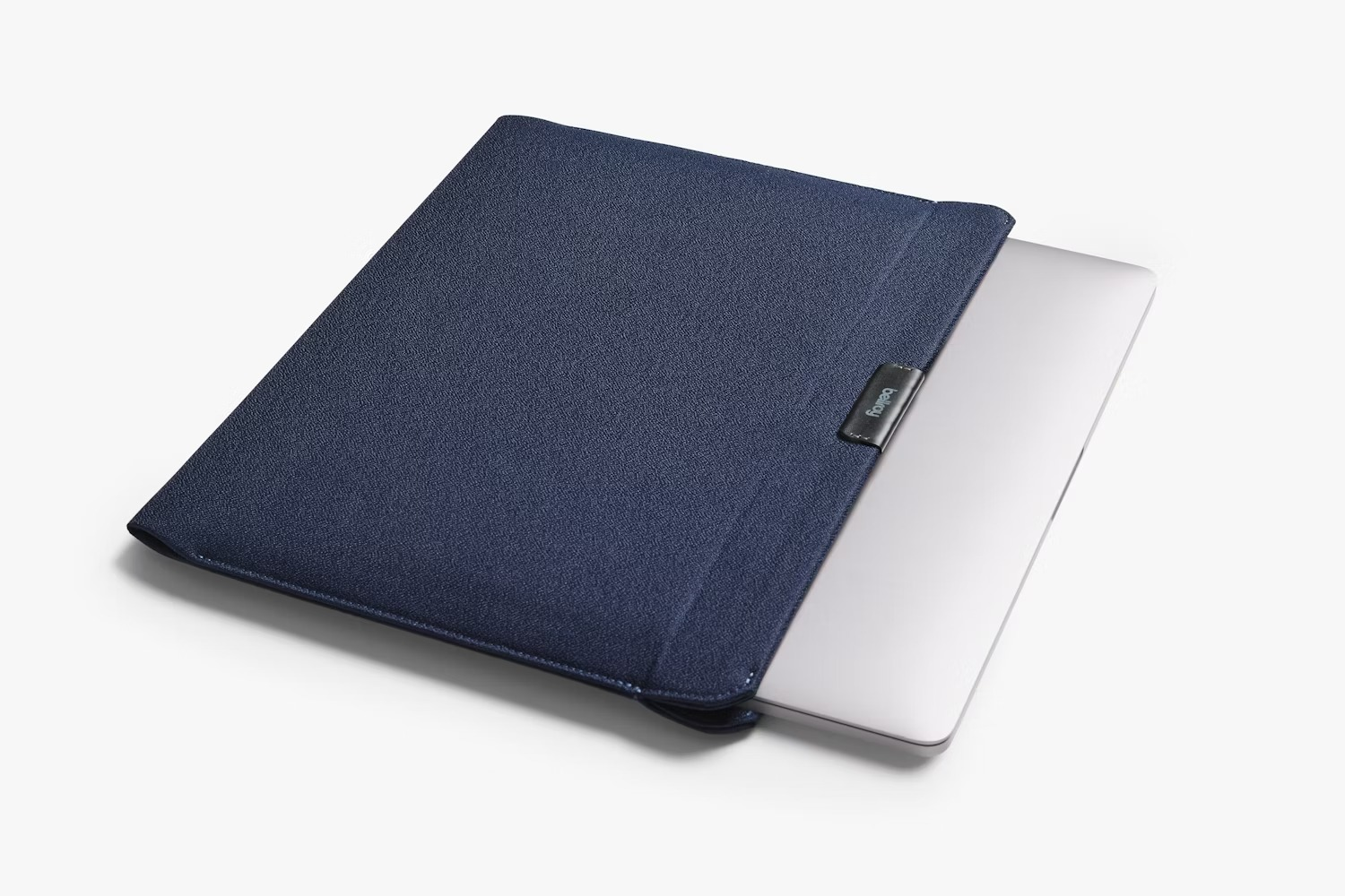 Srebrny laptop jest częściowo wsunięty w niebieski materiałowy pokrowiec na białym tle.