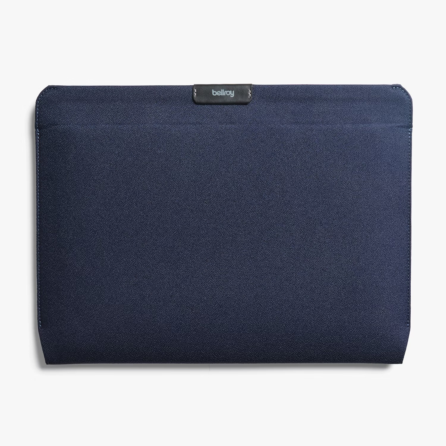 Ciemnoniebieskie etui na laptopa Bellroy ze skórzaną szlufką na górze na białym tle.