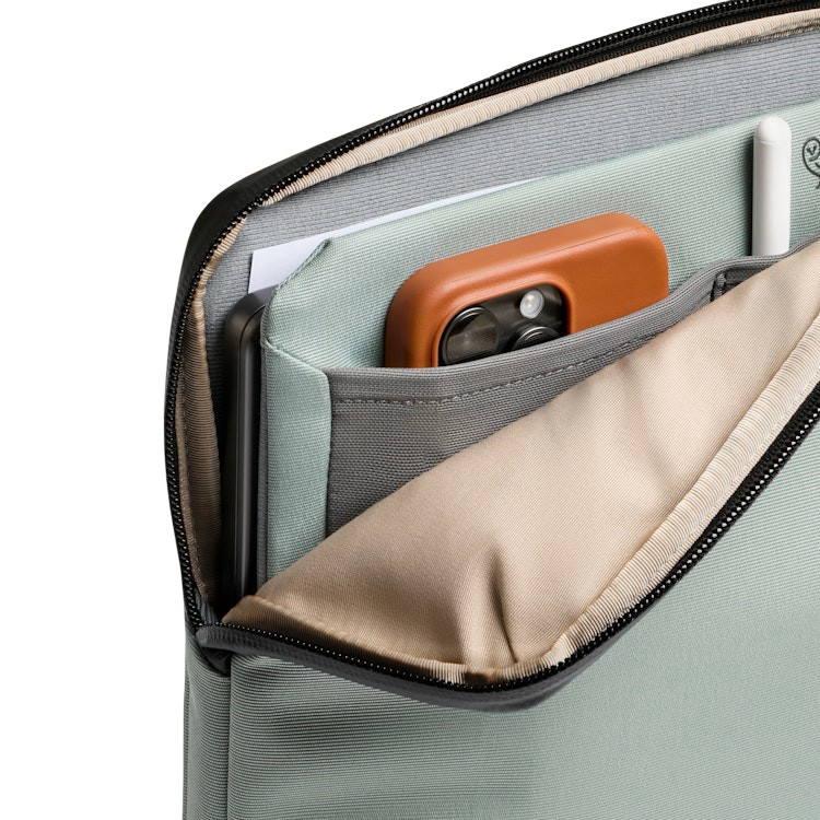 Otwarte etui na laptopa w kolorze szałwiowej zieleni mieści telefon w brązowym etui, tablet i biały rysik.