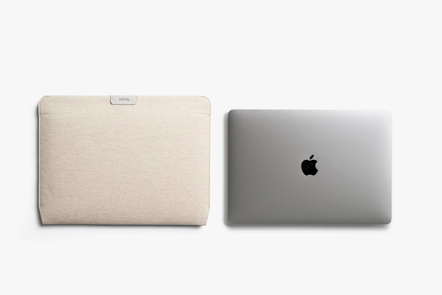 Beżowe etui na laptopa Bellroy i zamknięty srebrny laptop z logo Apple na białym tle.