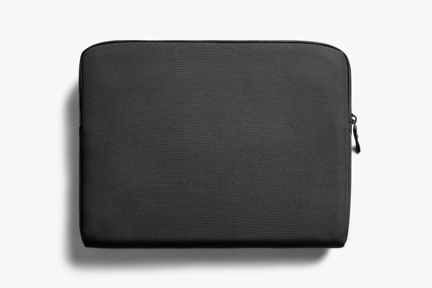 Czarne etui na laptopa na białym tle z widocznym zamkiem błyskawicznym.