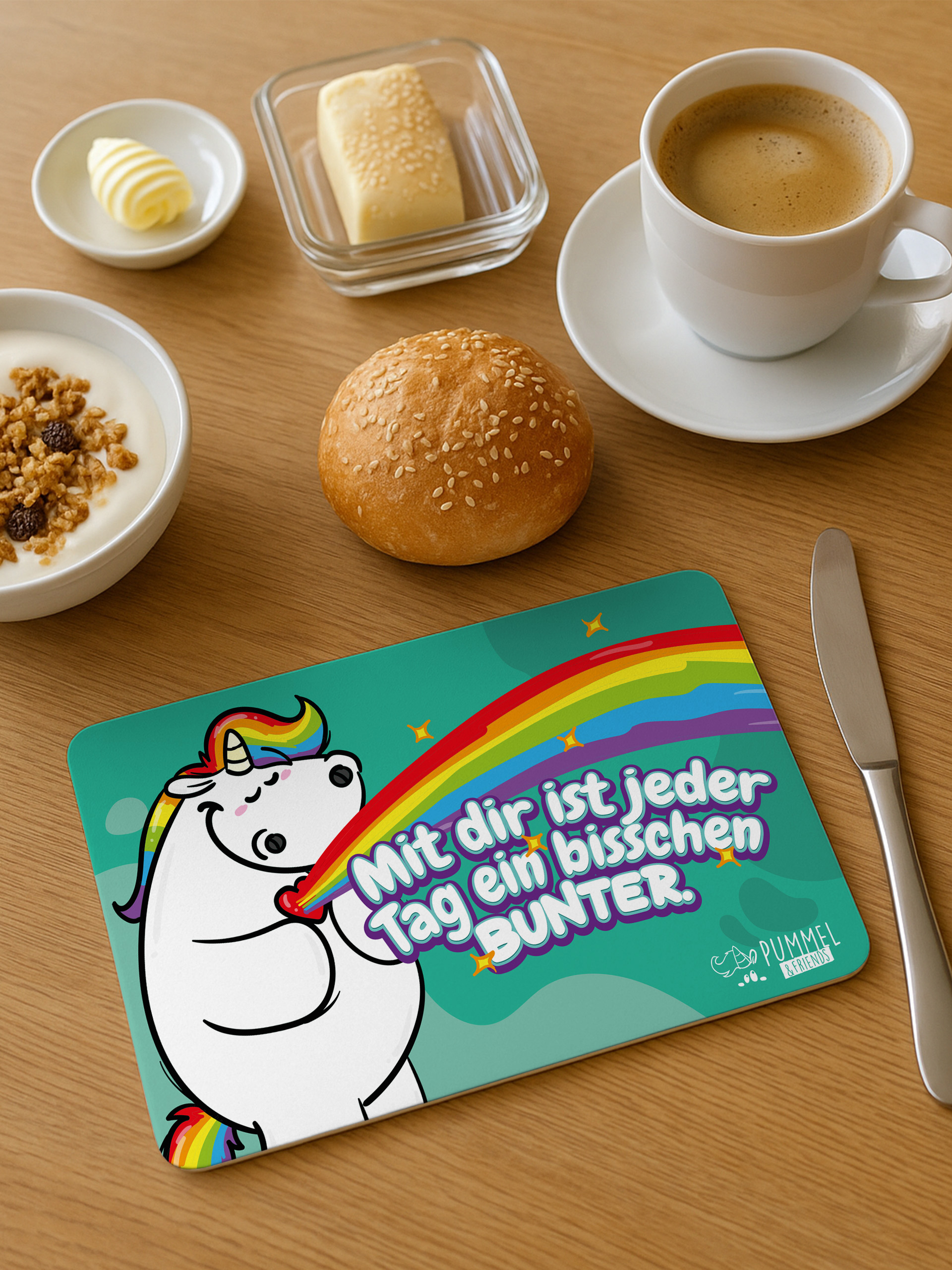 Frühstückstisch mit Kaffee, Brötchen, Joghurt und einer Einhorn-Platzset.