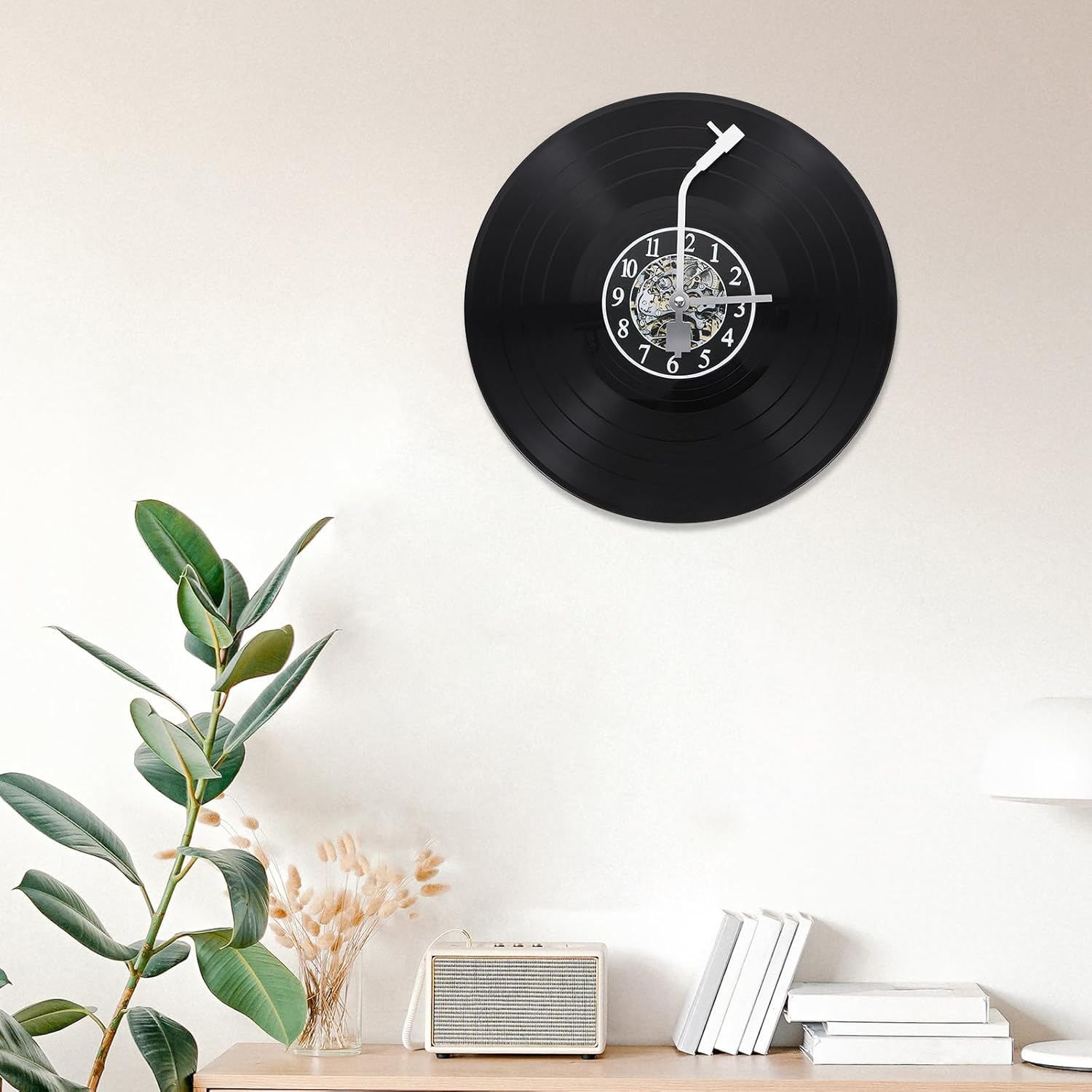 Eine schwarze Schallplatten-Wanduhr hängt an einer weißen Wand über einem Regal mit Pflanzen und Büchern.