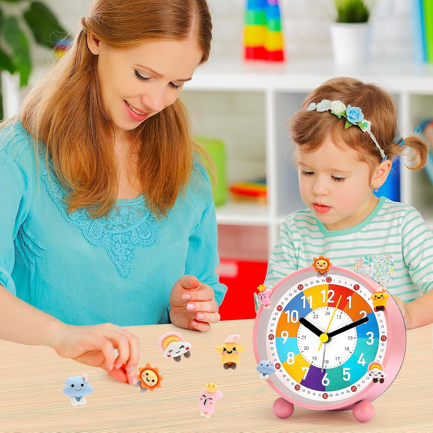 Eine Frau und ein Mädchen spielen am Tisch mit kleinen bunten Figuren neben einer bunten Lernuhr.