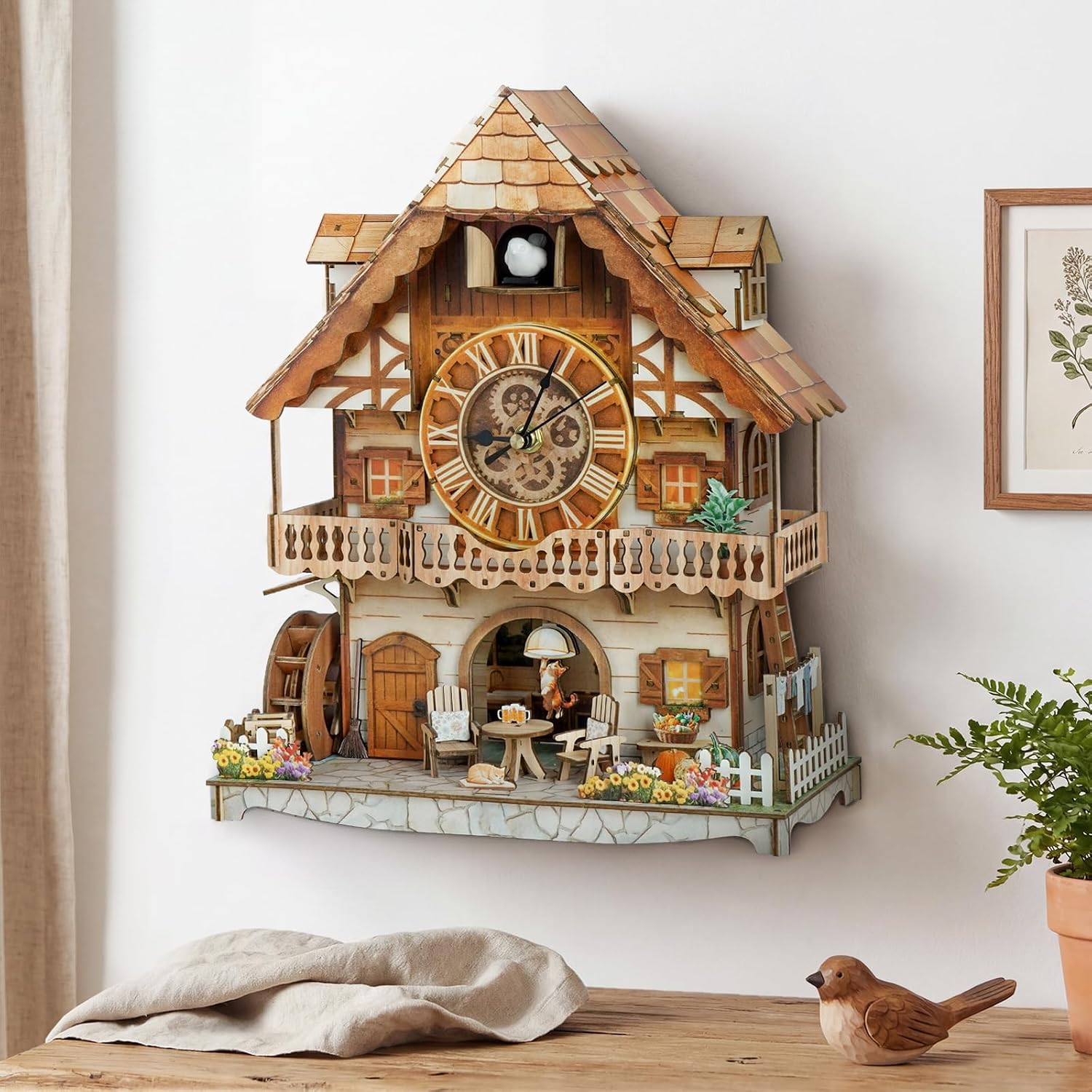 Ein detailreiches, hölzernes Kuckucksuhr-Modell im Chalet-Stil mit Balkon, Uhrwerk und kleinen Figuren auf weißer Wand.