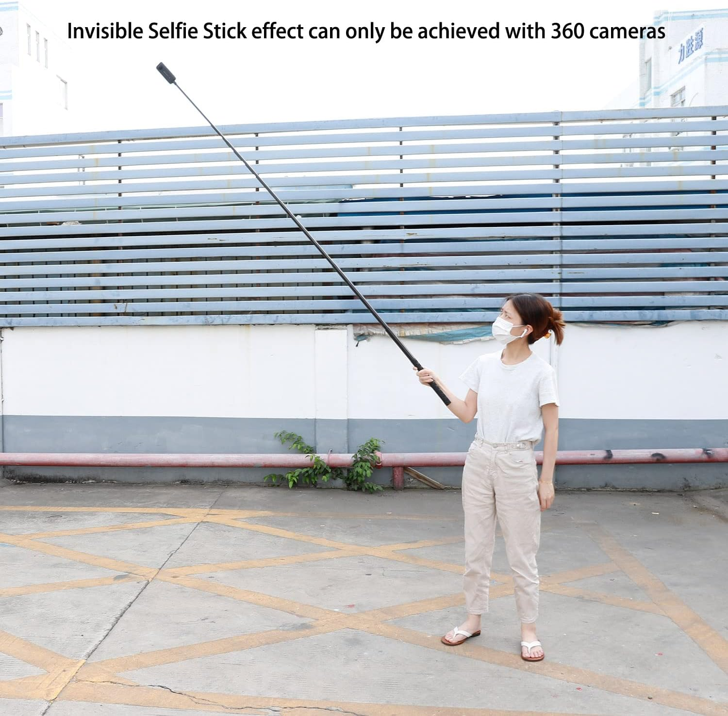 Eine Frau mit Maske hält einen extrem langen Selfie-Stick im Freien.