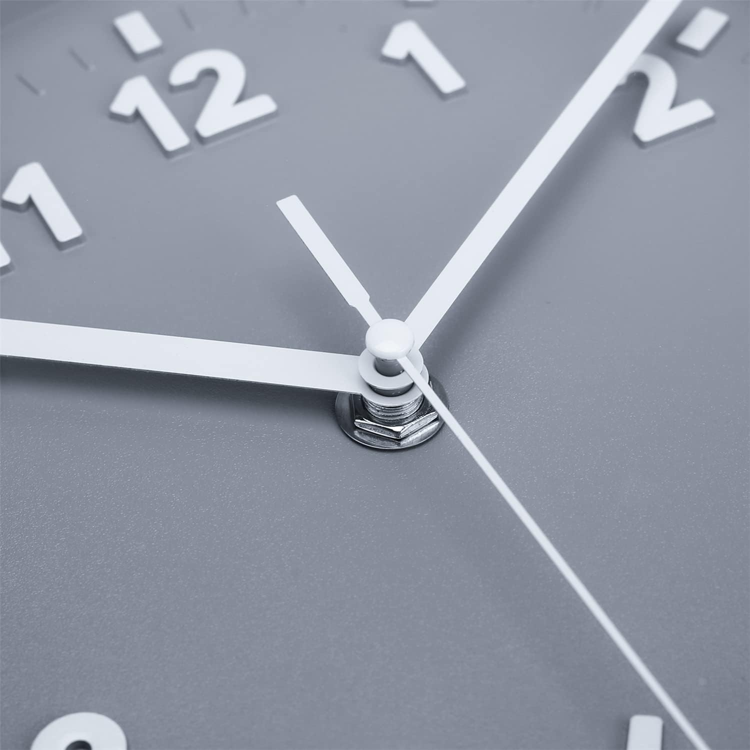 Nahaufnahme einer grauen Wanduhr mit weißen Zeigern und Ziffern.