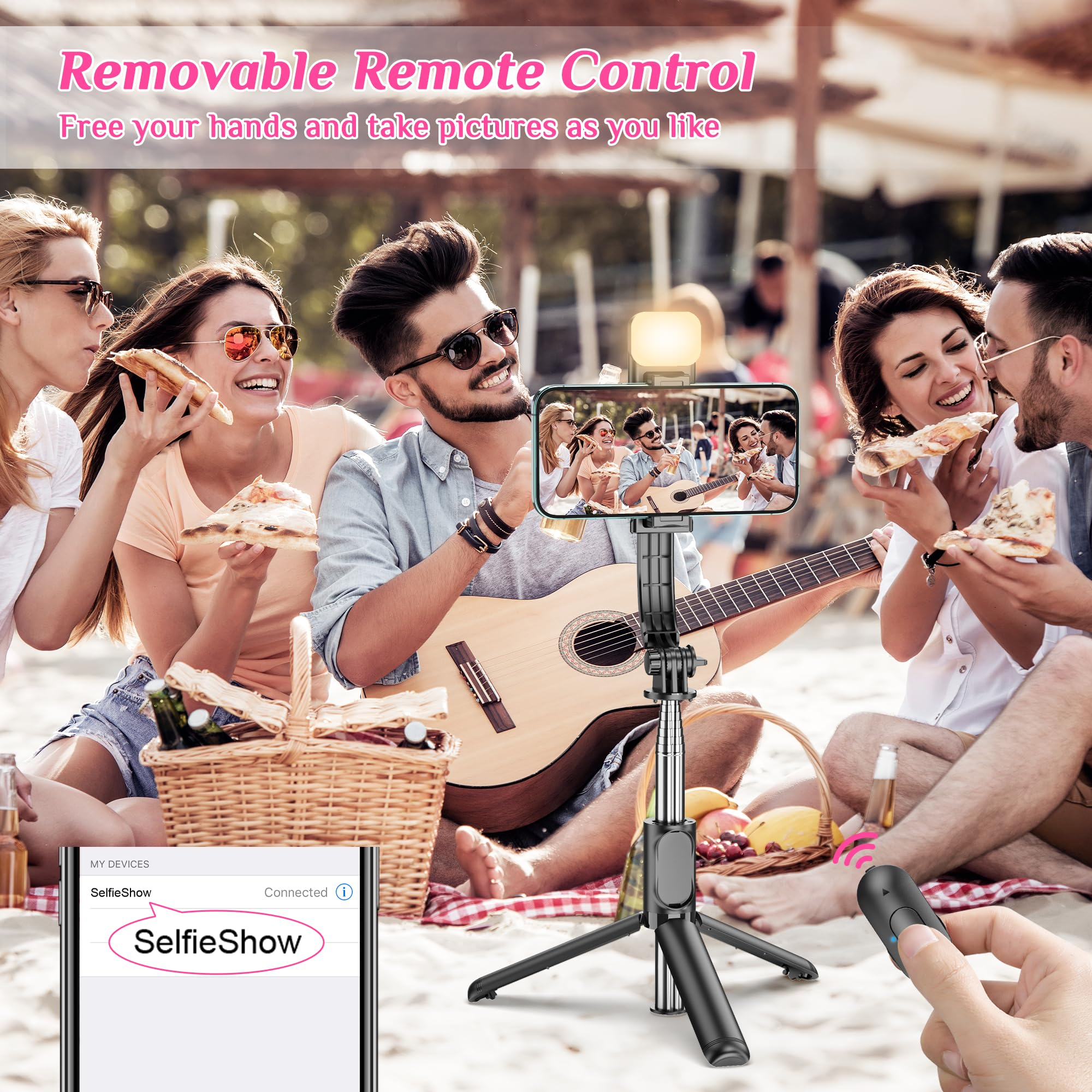 Gruppe von Freunden isst Pizza und spielt Gitarre am Strand, aufgenommen mit einem Selfie-Stick.