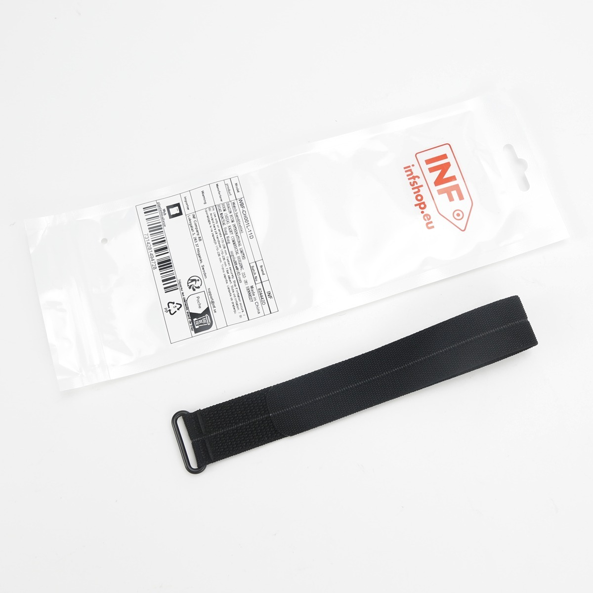 Ein schwarzes Stoffarmband liegt neben seiner klaren Plastikverpackung mit Produktetikett.