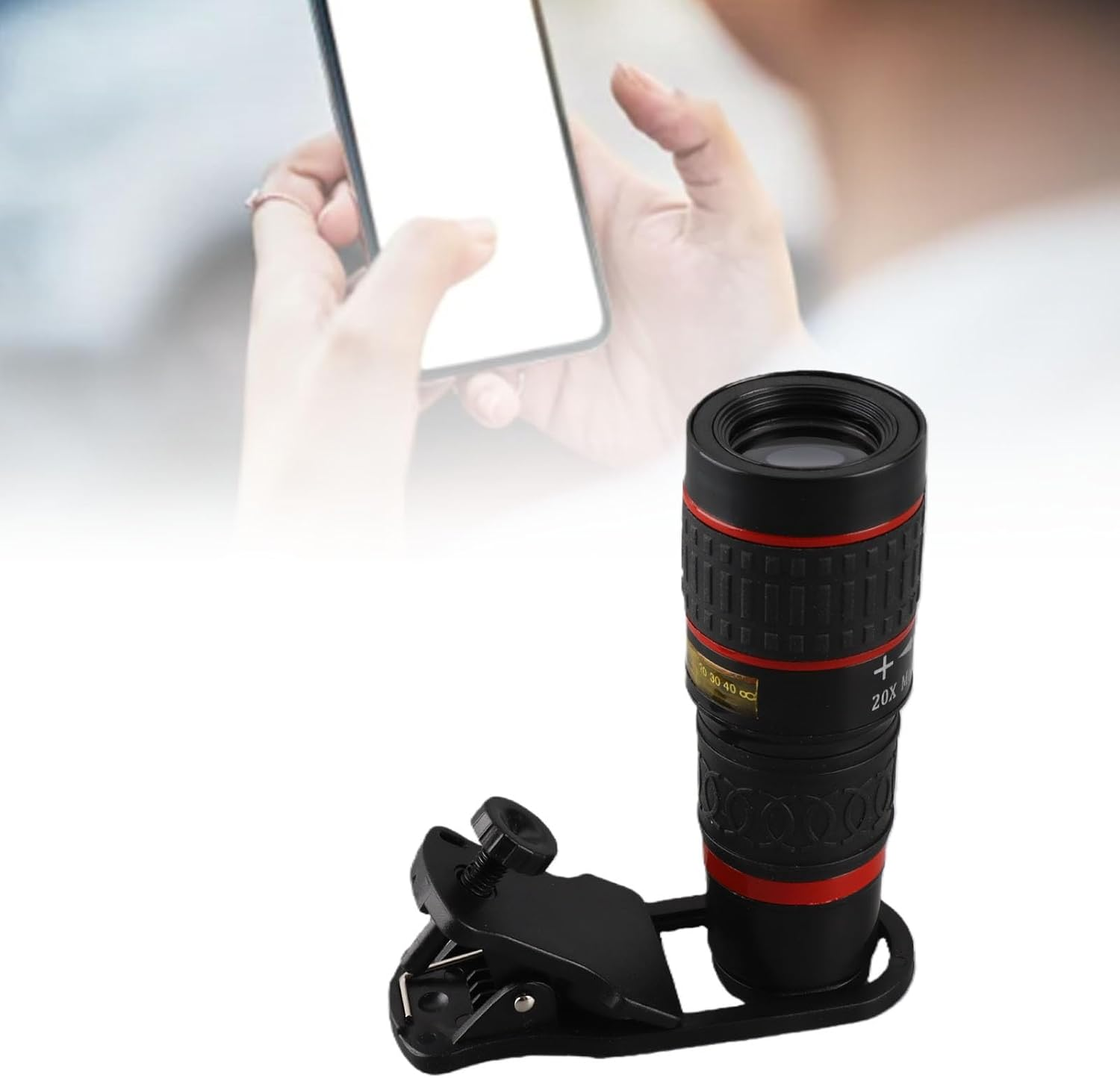Ein schwarzes Smartphone-Teleobjektiv mit rotem Ring und Befestigungsclip im Vordergrund.